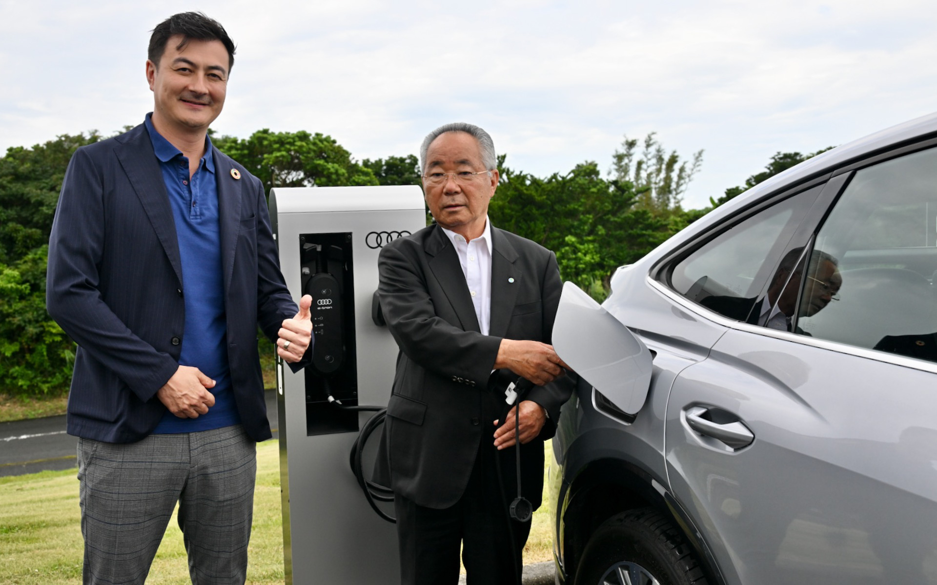 屋久島町役場に新たに設置された設備で充電を行なう屋久島の荒木耕治町長（右）とアウディジャパン ブランド ディレクターのマティアス・シェーパース氏