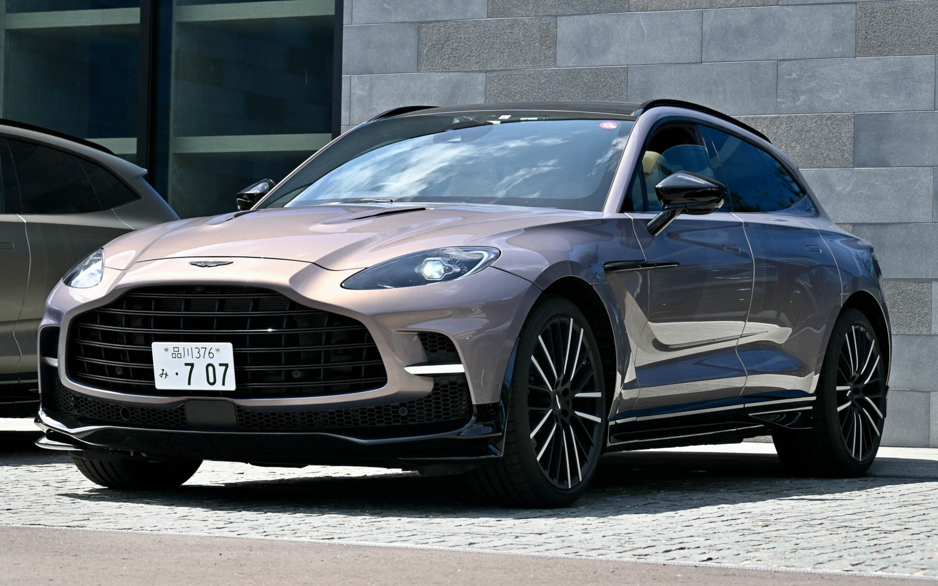 ボディサイズは5039×1998×1680mm（全長×全幅×全高）、ホイールベースは3060mmで、乾燥重量は2245kg。23インチのホイール内に収められるブレーキはフロント420×40mmディスク、リア390×32mmディスクを採用。ブレーキディスクはカーボンセラミック製のベンチレーテッド＆溝付き2ピース、セミフローティング構造で、キャリパーはフロントがアルミニウム製フロント6ピストン・モノブロックキャリパー、リアがアルミニウム＆鋳鉄製スライディング・シングルピストンキャリパー、一体型パークブレーキとなる。フロントとリアにはクローム加工の真鍮とエナメル製の手仕上げのアストンマーティン・バッヂを装着