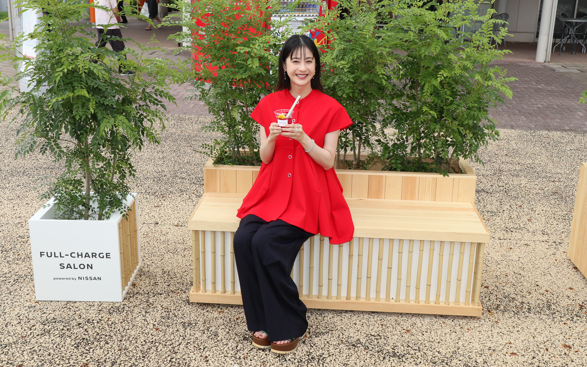 レストスペースのベンチに座ってスペシャルチャージドリンクをアピールする松本さん