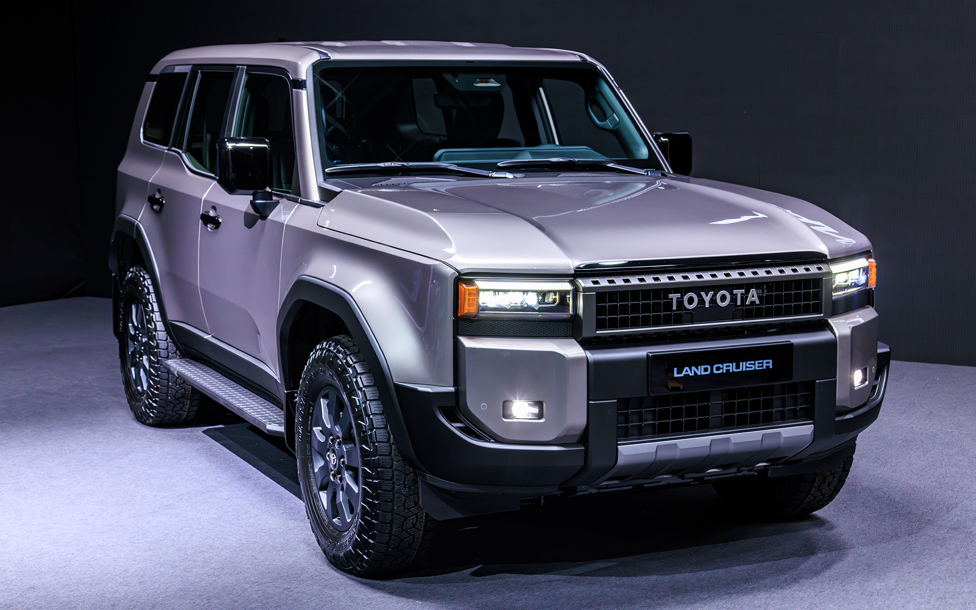 ボディサイズはランドクルーザー“300”シリーズ並みの4925×1980×1870mm（全長×全幅×全高）。バンパー形状により対地障害角を確保するほか、ドア下部をそぎ落とすことによってボディサイドへの干渉も低減する。フォグランプ横の樹脂部分のインテークは実際に穴が空いており、タイヤ面に空気を流すことで整流効果を狙ったもの。実際、大きくフロントウインドウも立ったフォルムながら従来型より空力性能はよいという