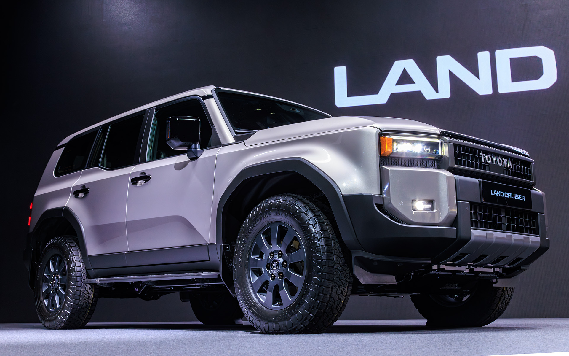 ボディサイズはランドクルーザー“300”シリーズ並みの4925×1980×1870mm（全長×全幅×全高）。バンパー形状により対地障害角を確保するほか、ドア下部をそぎ落とすことによってボディサイドへの干渉も低減する。フォグランプ横の樹脂部分のインテークは実際に穴が空いており、タイヤ面に空気を流すことで整流効果を狙ったもの。実際、大きくフロントウインドウも立ったフォルムながら従来型より空力性能はよいという