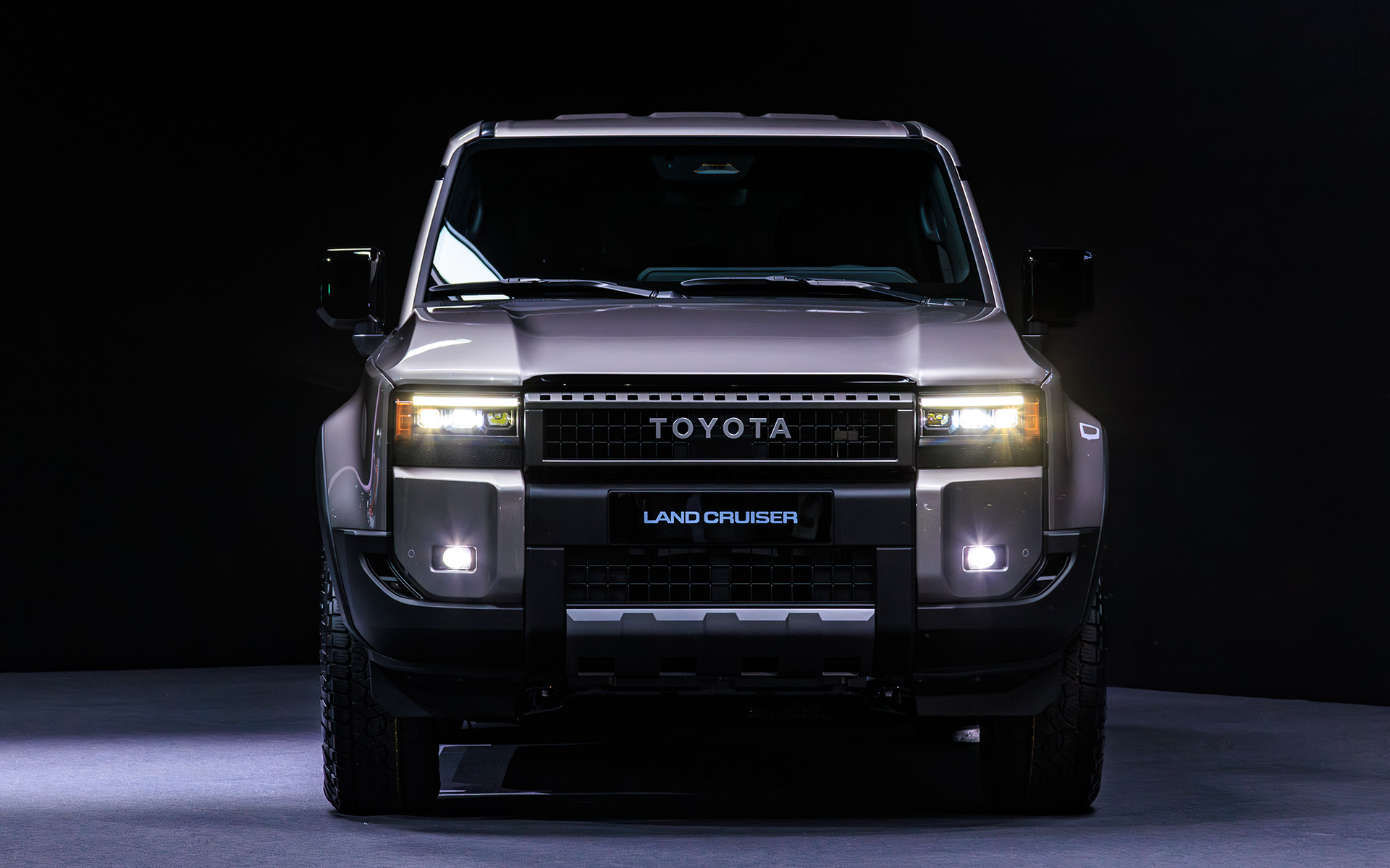 ボディサイズはランドクルーザー“300”シリーズ並みの4925×1980×1870mm（全長×全幅×全高）。バンパー形状により対地障害角を確保するほか、ドア下部をそぎ落とすことによってボディサイドへの干渉も低減する。フォグランプ横の樹脂部分のインテークは実際に穴が空いており、タイヤ面に空気を流すことで整流効果を狙ったもの。実際、大きくフロントウインドウも立ったフォルムながら従来型より空力性能はよいという