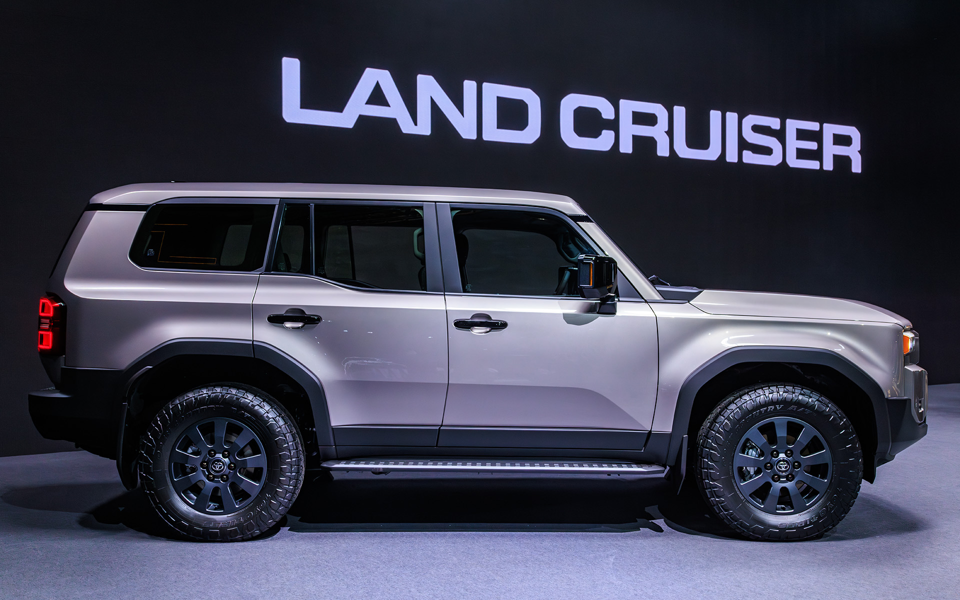 ボディサイズはランドクルーザー“300”シリーズ並みの4925×1980×1870mm（全長×全幅×全高）。バンパー形状により対地障害角を確保するほか、ドア下部をそぎ落とすことによってボディサイドへの干渉も低減する。フォグランプ横の樹脂部分のインテークは実際に穴が空いており、タイヤ面に空気を流すことで整流効果を狙ったもの。実際、大きくフロントウインドウも立ったフォルムながら従来型より空力性能はよいという