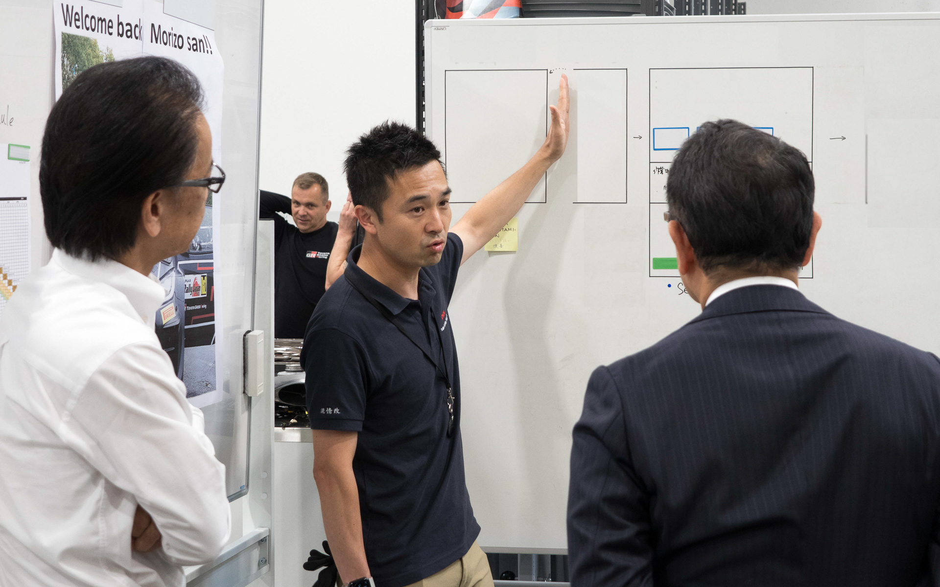 TGR-WRTにおけるTPSの説明を受ける豊田会長。会長越しに見えるのが工程分解されたKOMA Board。その後、会長からTPSについてのカイゼン策が語られた