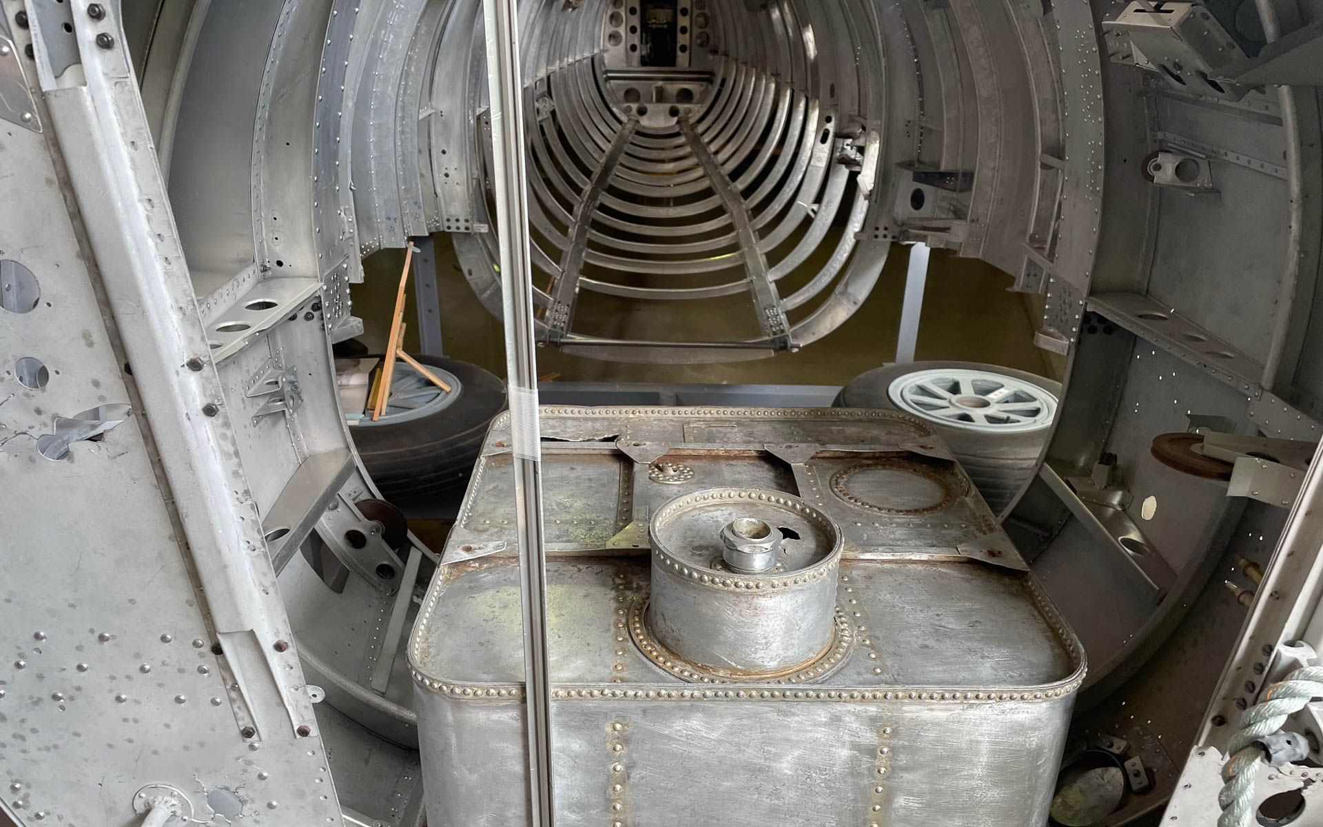 エンジン側から胴体内部を覗く。手前の箱は70L入りのオイルタンク。収納された車輪の位置や、内部のリブ構造が分かる