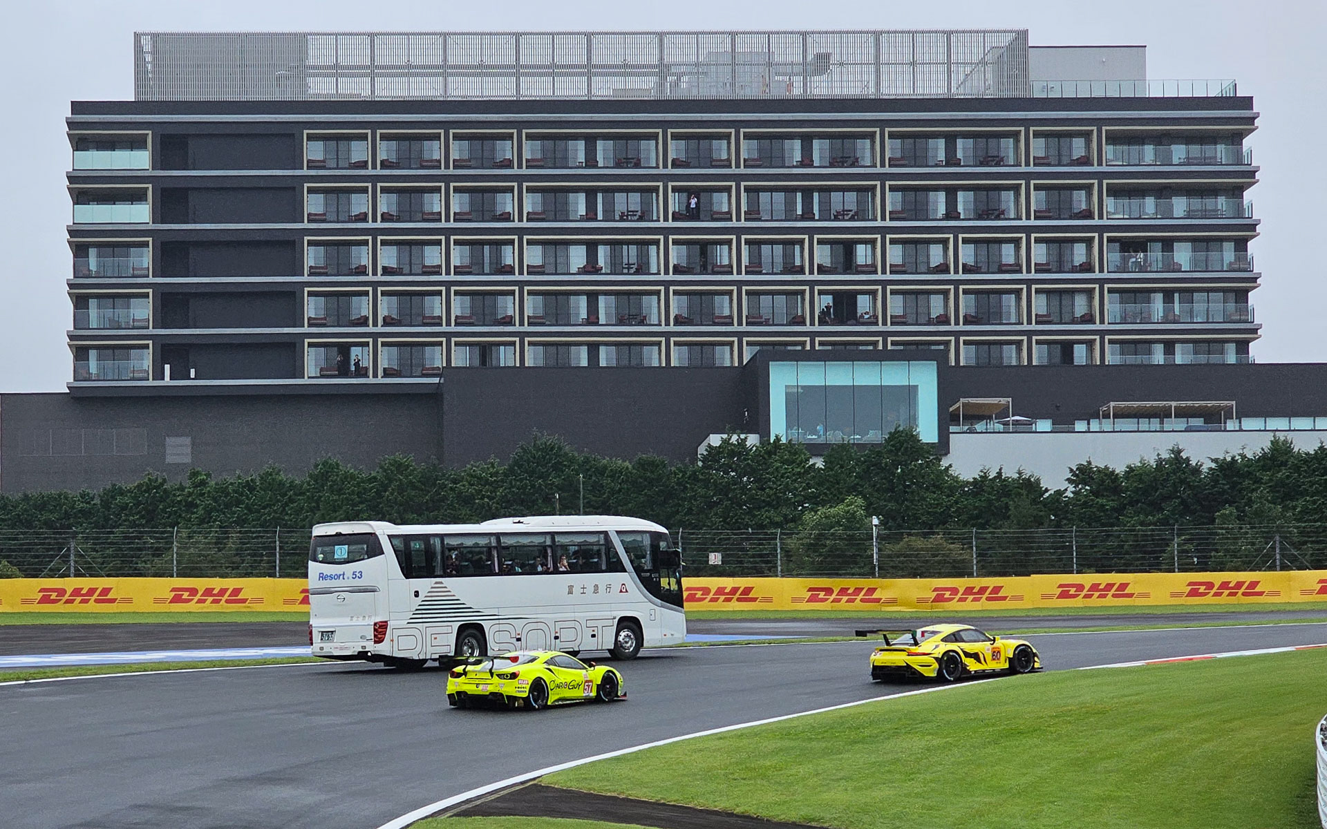 観光バスのすぐ横をレーシングカーが駆け抜けていく