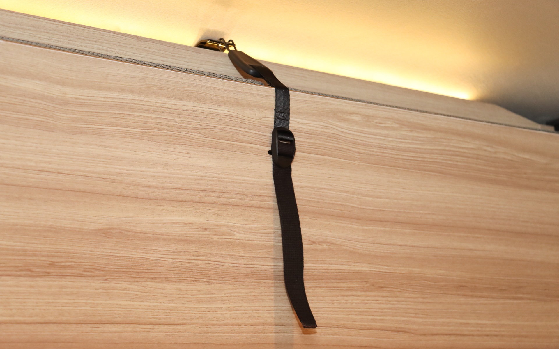 跳ね上げベッドはフックで固定されているだけ。下のヒンジ部分にダンパー機能が内蔵されており、フックを外すだけで簡単に展開できる