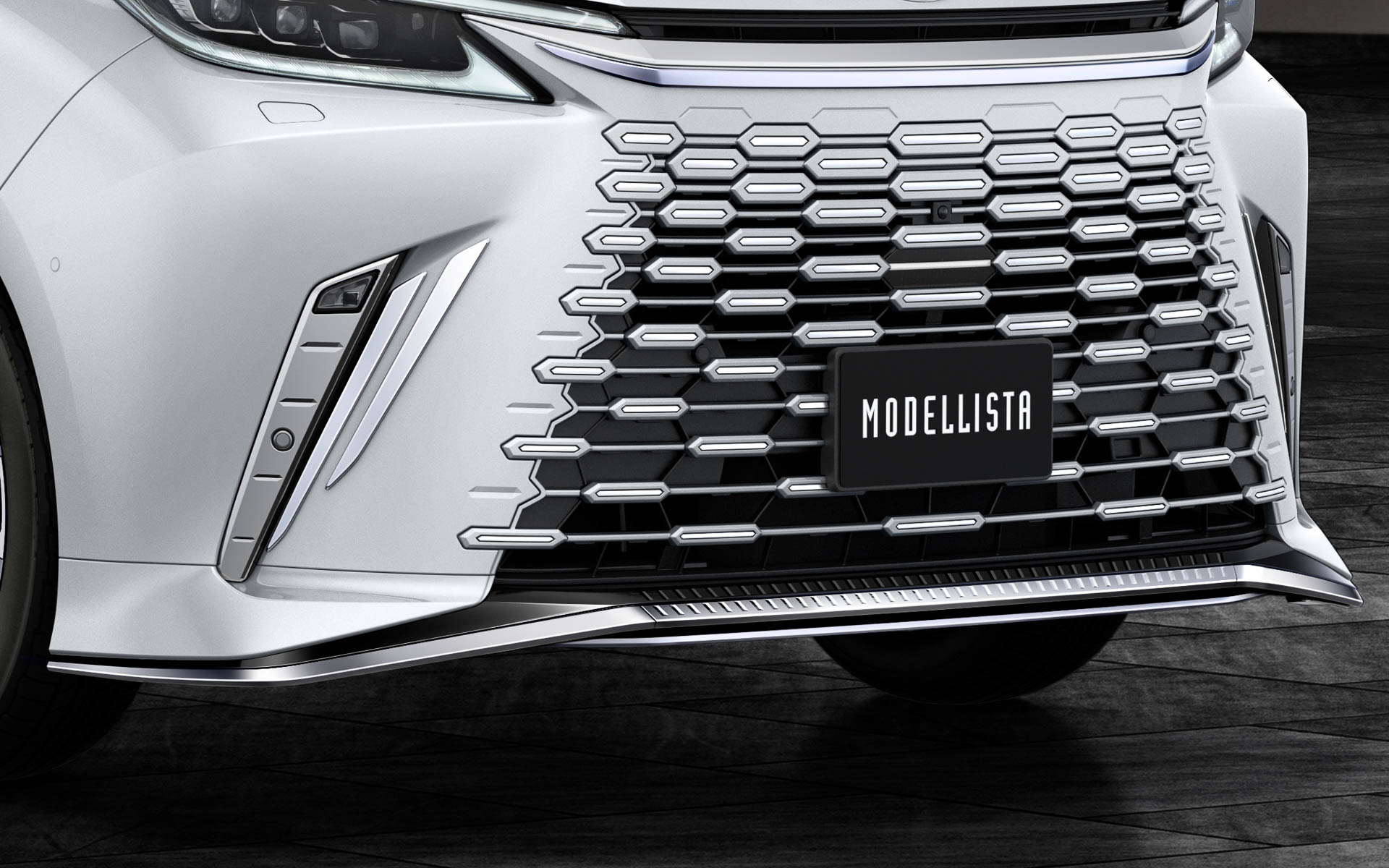 フロントスポイラーは、センターからサイドに流れるダイナミックな造形テーマで、堂々としたたたずまいと威厳のあるフロントフェイスを創出。中央部のスリット造形は先進感あるフロントフェイスをより際立たせるとともに、太陽光を反射してきらびやかな表情を演出する