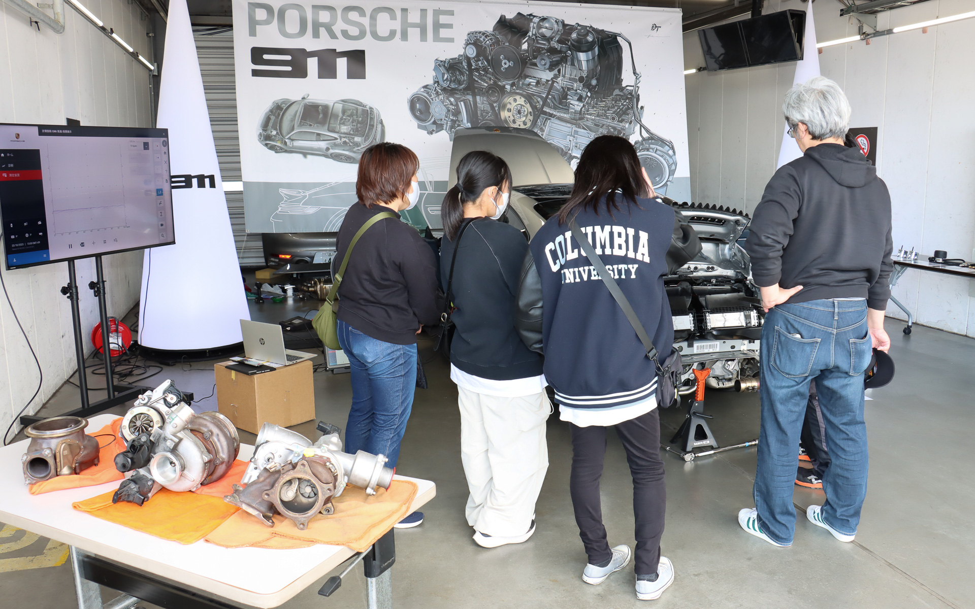 露出させた911のエンジンまわりを紹介しながら現代と過去のポルシェモデルの違いなどを説明