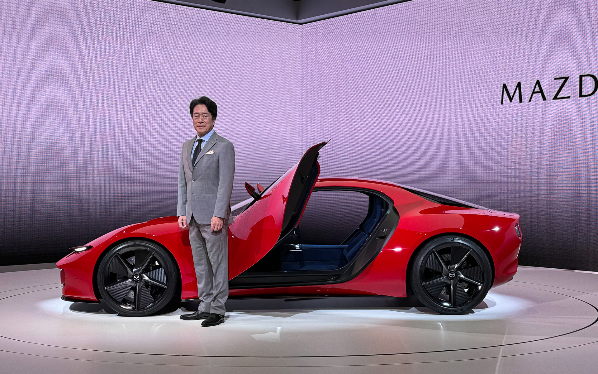 2ローターRotary-EVシステム搭載コンパクトスポーツカーコンセプト「アイコニック SP」のドアは前方へ跳ね上げるタイプ。代表取締役社長兼CEO 毛籠勝弘氏とともに