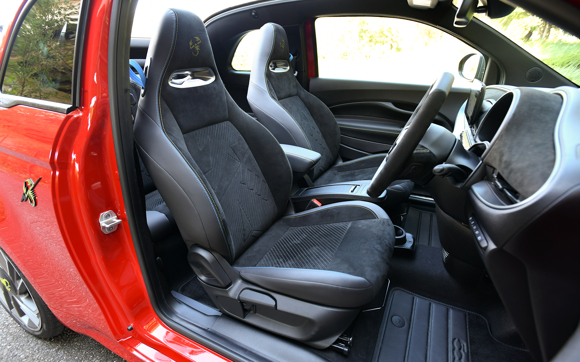 黒を基調としたシックでスポーティなインテリア。インストルメントパネル、ステアリング、ヘッドレスト一体型スポーツシートなどにアルカンターラ素材を採用し、高級感を演出。ヘッドレストには「Abarth 500e」専用のロゴをあしらい、ブルーとイエローのステッチを施した一体型のスポーツシート、ステアリングホイールにあしらったブルーのトップマークとともにスポーティさを高めている