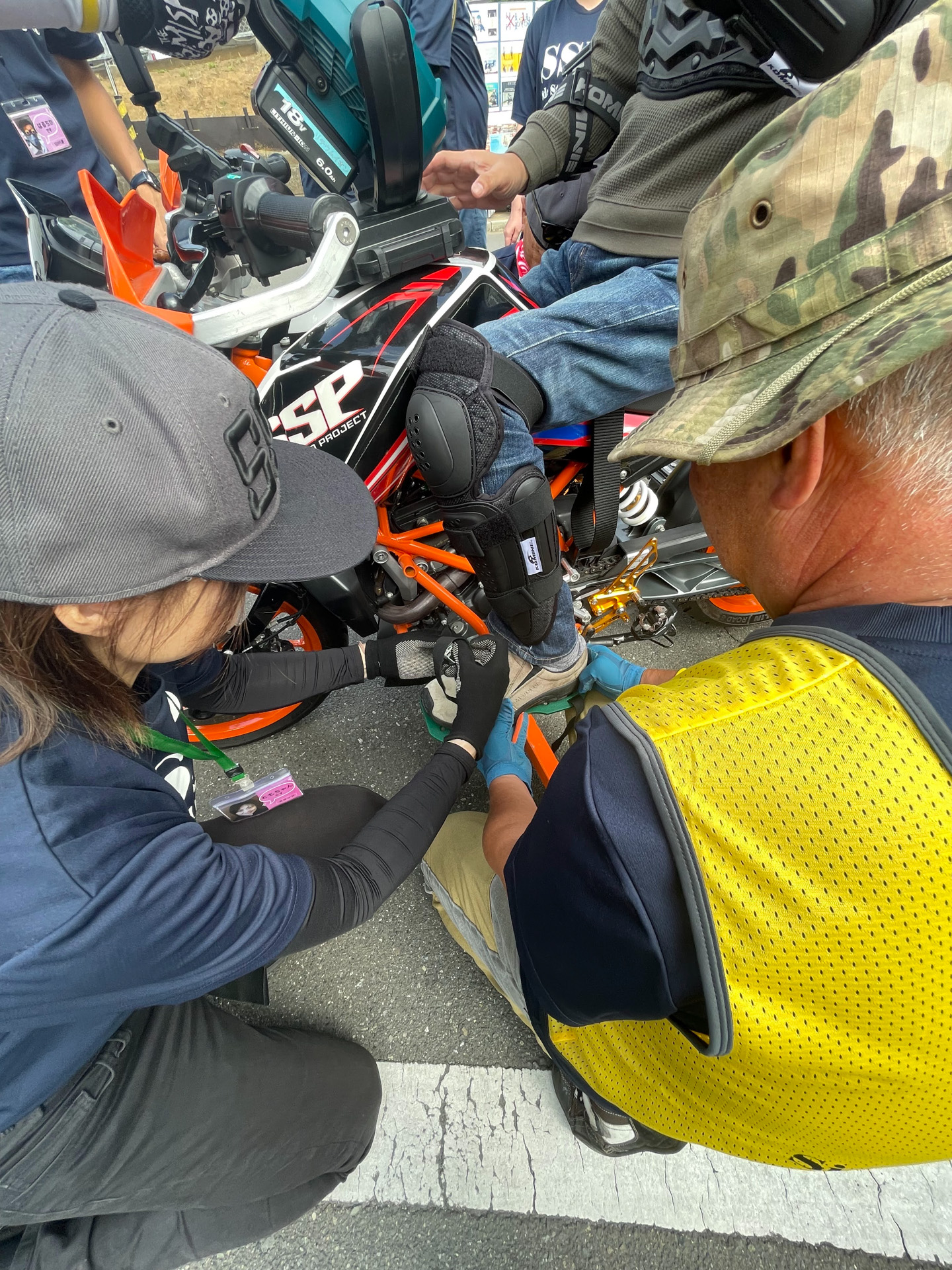 スタッフさんに抱え上げられて車いすからバイクに移動。足もビンディングにセットしてもらう