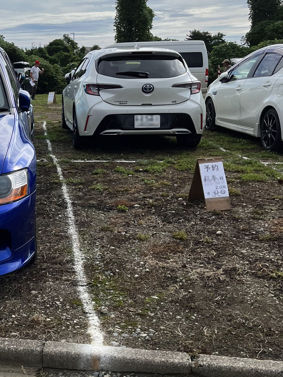 H：3000円の看板はUターンして、突き当たりを道なりに右折した先の駐車場と思われる。各区画に予約表示あり。ここはSUPER GT開催時も運営している。道伯1丁目の交差点経由でサーキット前交差点まで1.4km