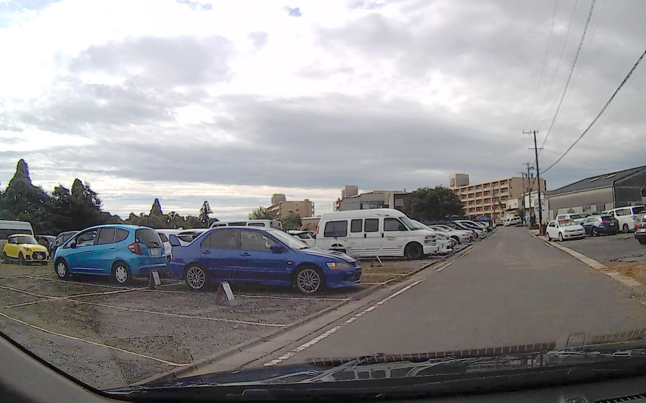 H：3000円の看板はUターンして、突き当たりを道なりに右折した先の駐車場と思われる。各区画に予約表示あり。ここはSUPER GT開催時も運営している。道伯1丁目の交差点経由でサーキット前交差点まで1.4km