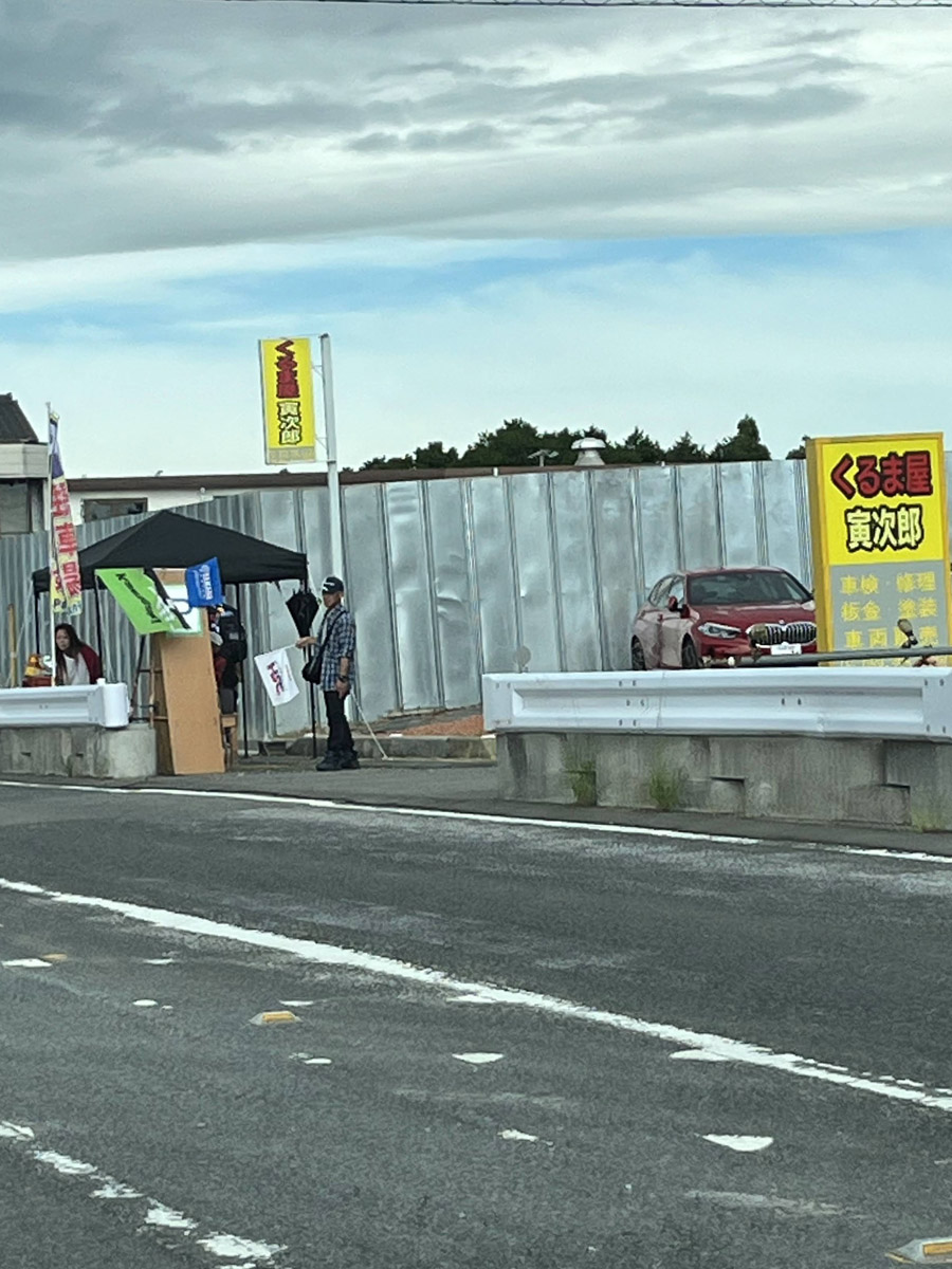 V：価格不明。中古車販売の駐車場。1コーナーゲートまで600m