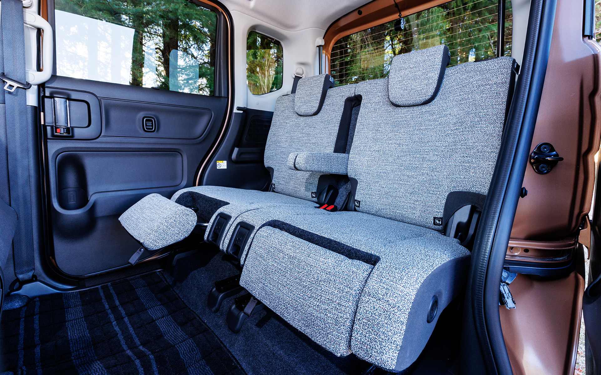 シート表皮は家具のような印象のカラーメランジを用いて、車内の心地よさを演出。後席にはスズキ初のギミック「マルチユースフラップ」が採用され、足を投げ出してリラックスできる「オットマンモード」、走行中の姿勢をサポートする「レッグサポートモード」、荷物の落下防止をサポートする「荷物ストッパーモード」の3つの機能を備える。スペーシアは子供の塾の送り迎えで利用されることもあるというアンケート結果から、車内で子供の帰りを待つ親が、後席でくつろぎながら自分時間を過ごせるようにと、マルチユースフラップが開発されたという