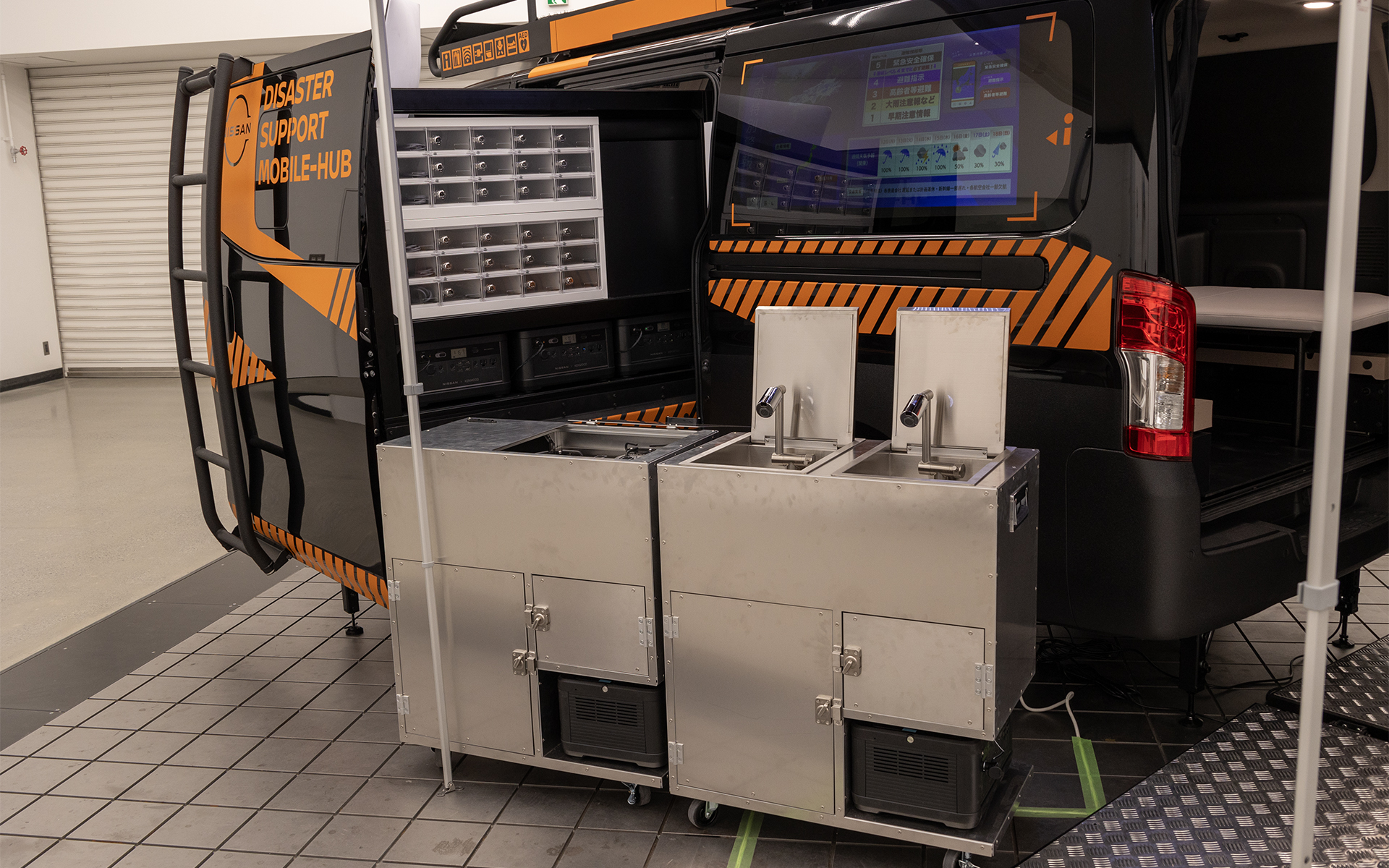 左面サポートエリア。引き出し式のブロックには「ポータブルバッテリーfrom LEAF」が複数収納。その上にはスマートフォンの充電ボックスがある。手前には可動式のギャレーを配置