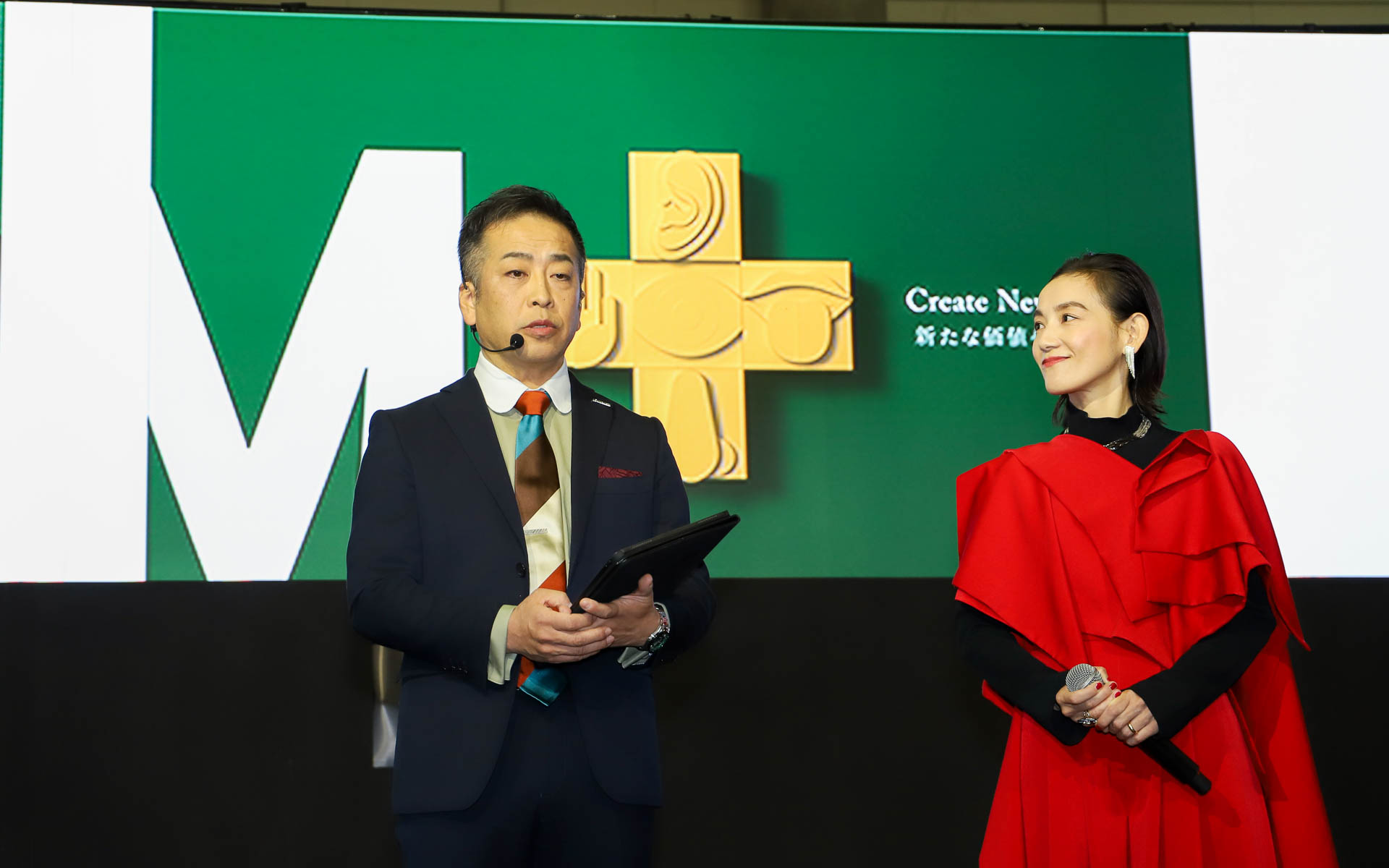 濱井氏と篠原さんの後方スクリーンに映っている「M＋」は、今後のモデリスタを示す“五感に響く機能価値”をビジュアル化したもの