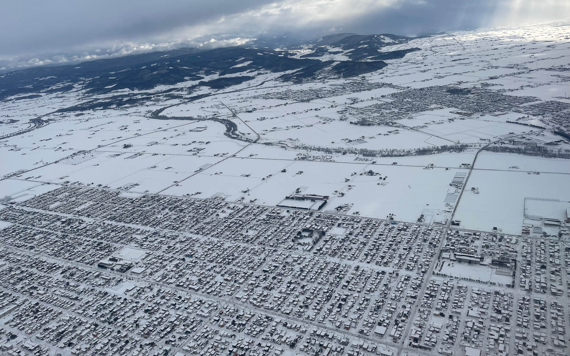 旭川市を空の上から。今年は雪が少なく、しかも重い雪が積もっていた。温暖化の影響だ