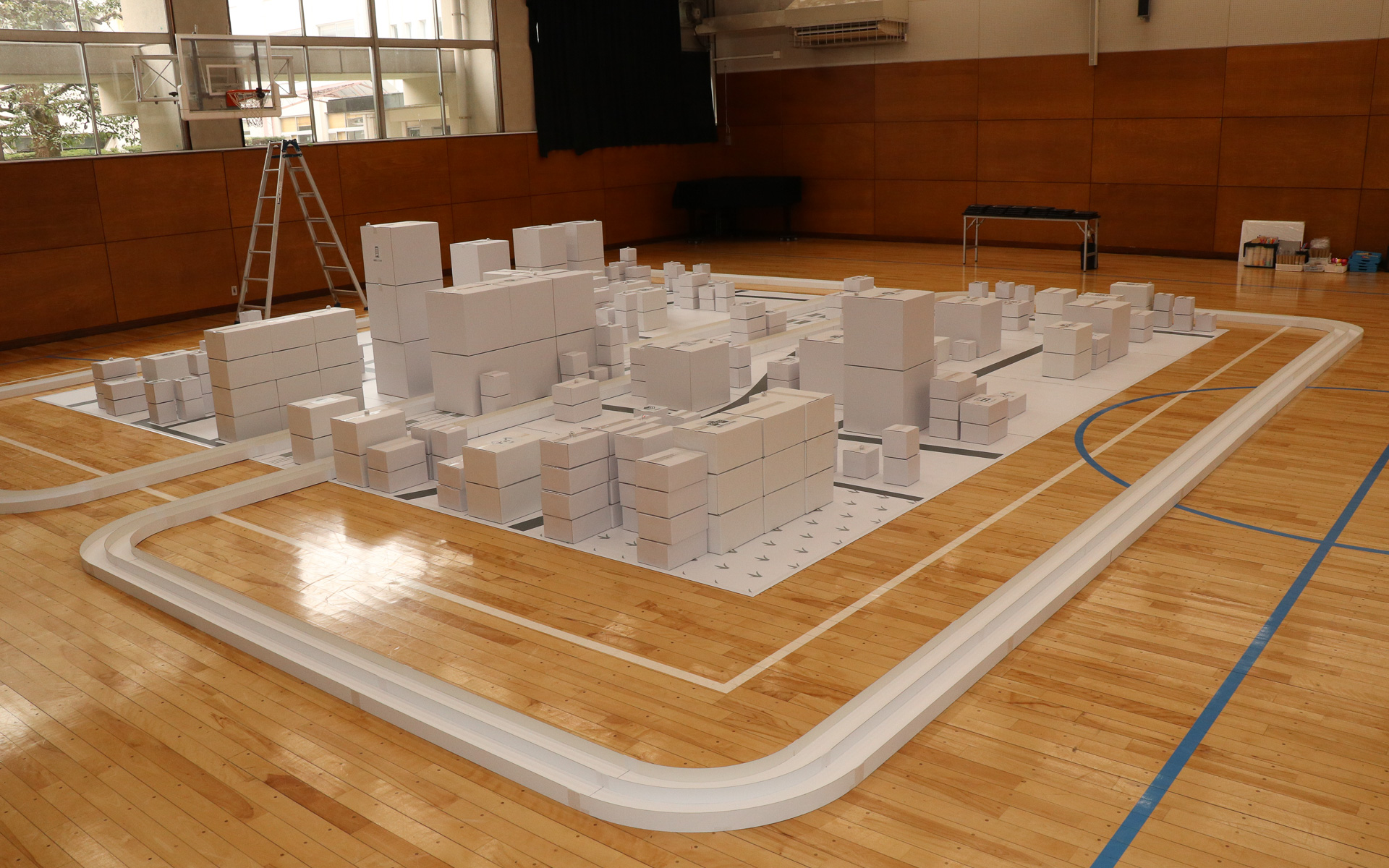 体育館内の7m四方のスペースで再現された“ミニチュア中野区”。白いダンボールを使って組み立てられ、子供たちが自由なアイデアを書き込んでいけるキャンバスとなっている