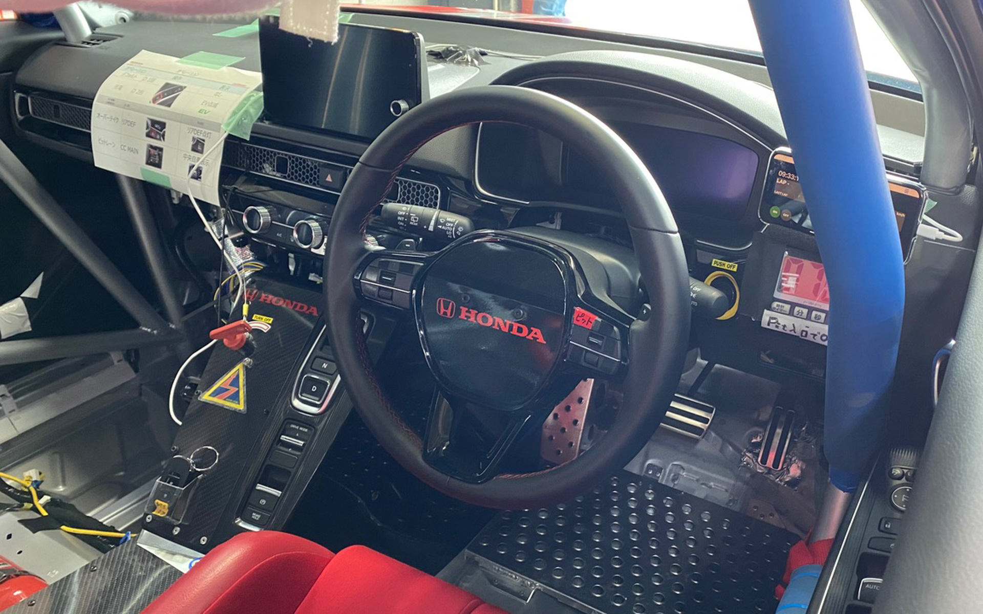 コクピットはこの通り、軽量化されたりロールバーが入ったり、すでにレーシングカーらしく変身。チーム監督の奥山さんの遊び心で、流れるウインカーがついているんですよ（笑）。制限速度が40km/hのピットロードで違反しないように、「ピットロードモード」のボタンも加わりました。ピットロードに入ってから40km/hに達するまでの加速は、はたから見ていてもめっちゃ速いです！
