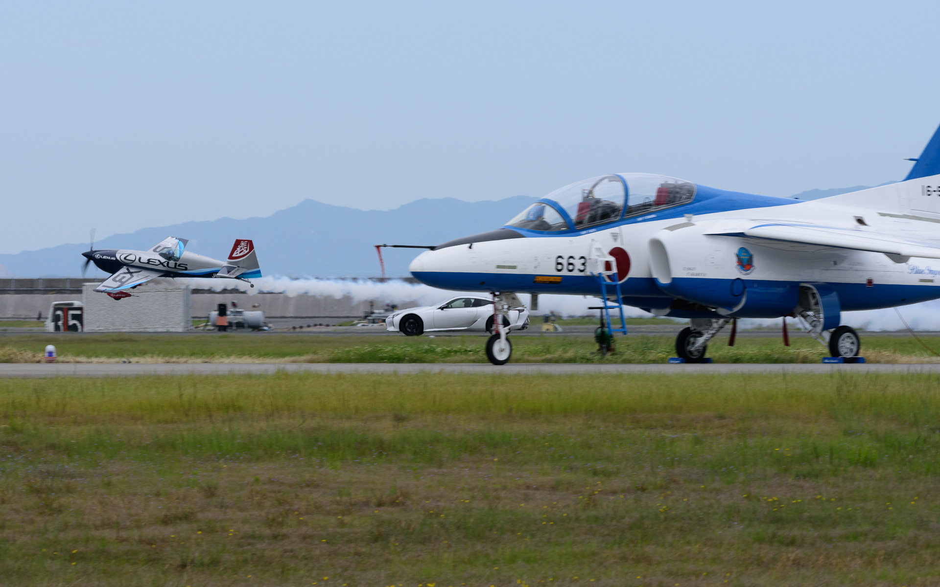 岩国フレンドシップデーに訪れたブルーインパルスの奥をレクサス車とともに駆け抜けていく室屋義秀選手