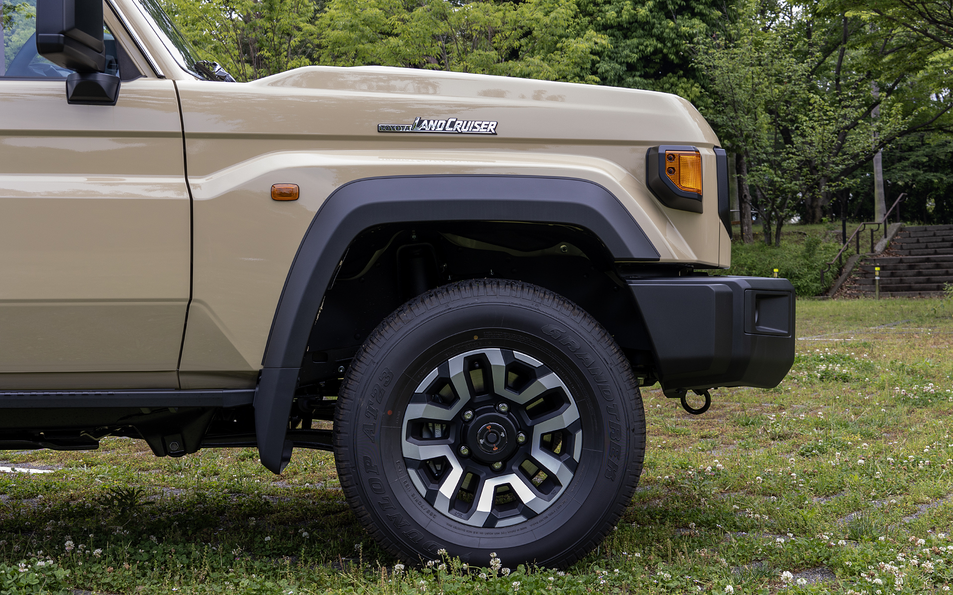 フロントタイヤ＆ホイール。タイヤは前後265/70R16 AT23。アルミホイールは16×7J。切削光沢＋ブラック＋マットクリア塗装仕上げで、センターオーナメントが付く