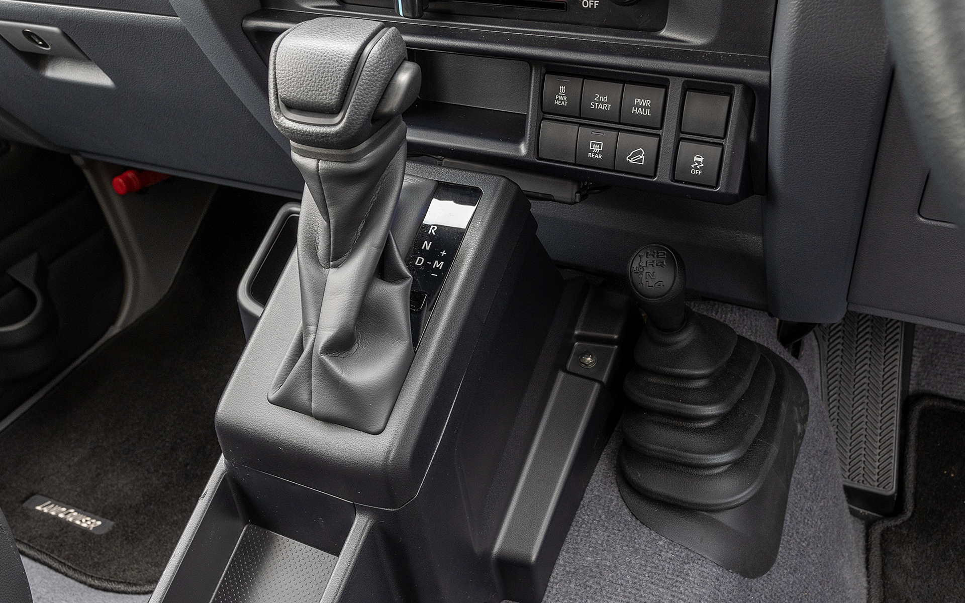 ATは通常のDモードのほかに任意のギヤを選択できるMモードもある。MモードはM1～M6までの間でギヤチェンジができる。奥に見えるのが駆動系の作動状態を切り替えるトランスファーレバー。4つのポジションがあり奥から「ハイレンジ2WD（通常はこの位置）」「ハイレンジ4WD」「ニュートラル」「ローレンジ4WD」となっている