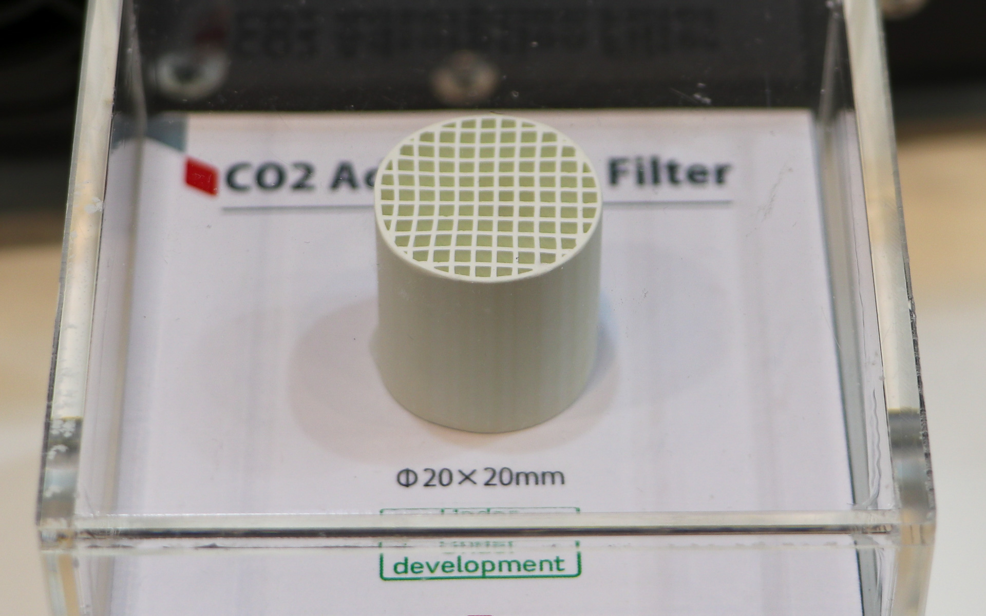 CO2吸着フィルタ。展示品はφ20×20mmと小さなものだが、乗用車の場合は従来のエアコンフィルタより少し大きい300mm×300mmくらいのサイズが必要になりそうとのこと