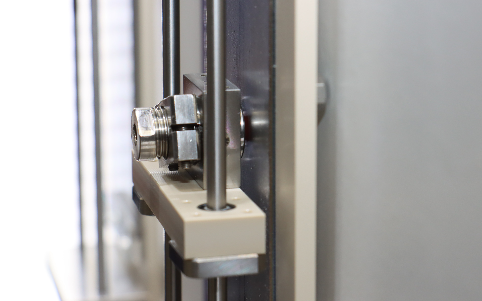 鉄板の上に貼り付けられているのが実際の従来ゴム（左）と自己潤滑ゴム（右）の実物。円盤形になっているゴムを半球状に押し付けて試験を行なう