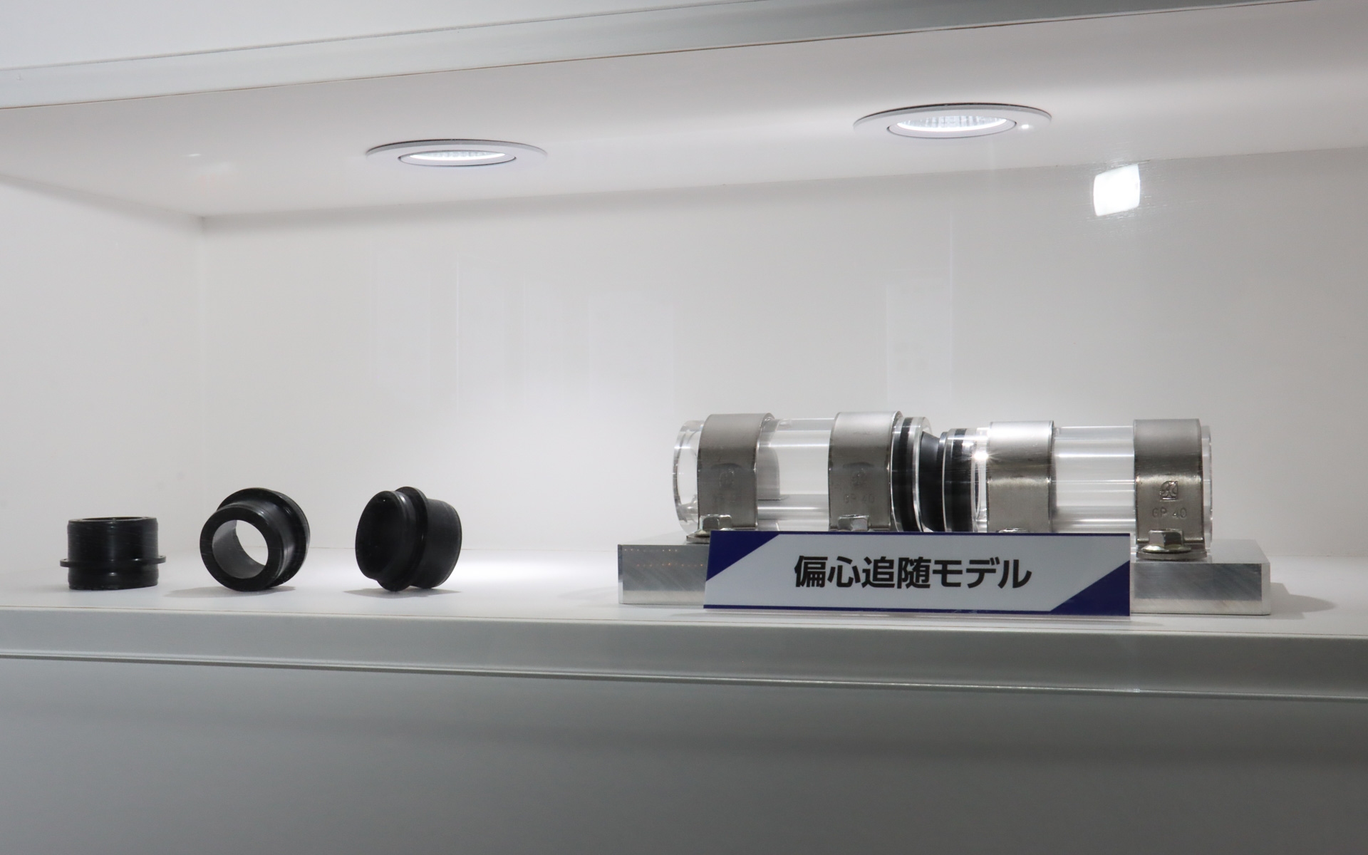 配管用継手シールのデモ展示。高さの異なる2本のパイプの間をつなぐ配管用継手シールは大きく斜めに変形しているが、ゴム嵌合部は歪むことなくパイプに密着している