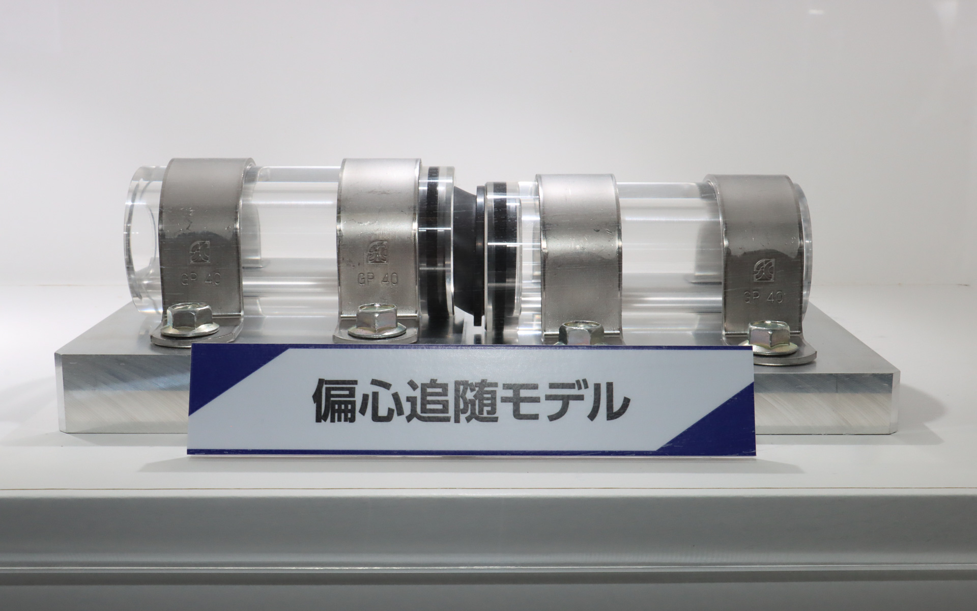 配管用継手シールのデモ展示。高さの異なる2本のパイプの間をつなぐ配管用継手シールは大きく斜めに変形しているが、ゴム嵌合部は歪むことなくパイプに密着している