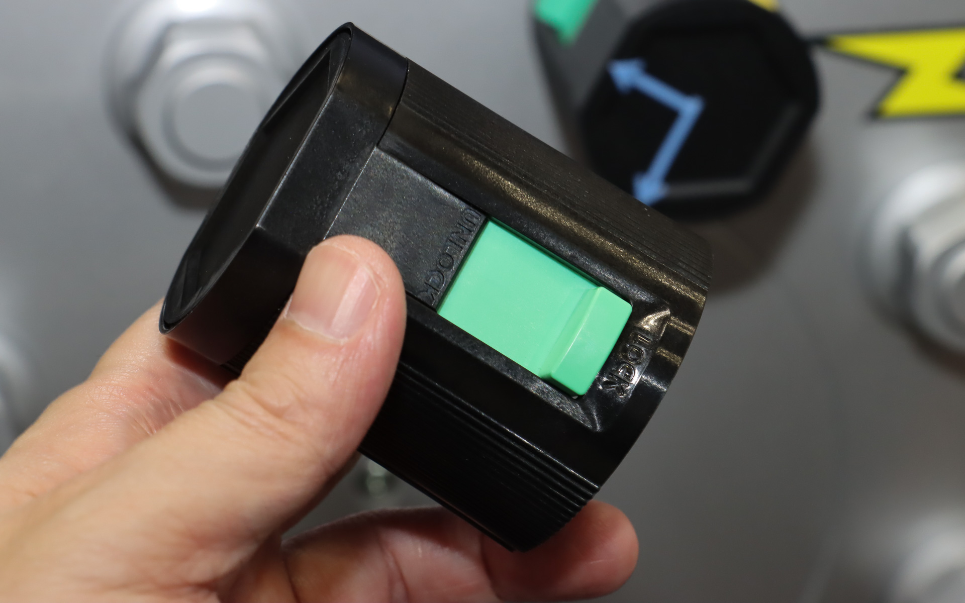 「ナットキャップセンサー」をホイールナットの上から被せ、緑色のスライドロックを押し込むだけで簡単に取り付けられる