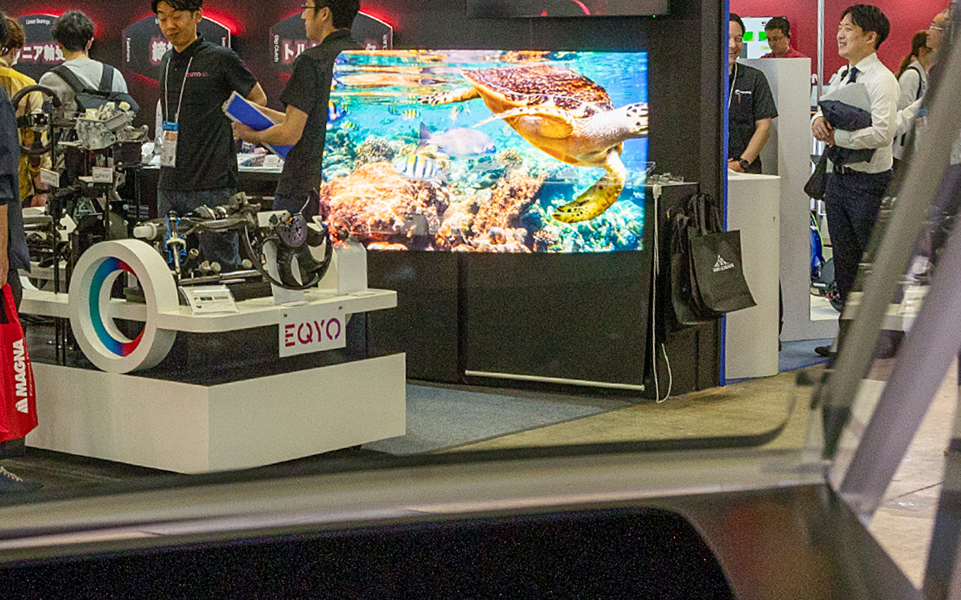 日本精機ブースに用意された「ARヘッドアップディスプレイ」。通路側に向けた展示なのでいろいろ写り込んでいるが、ウミガメが写っているのがARヘッドアップディスプレイの表示