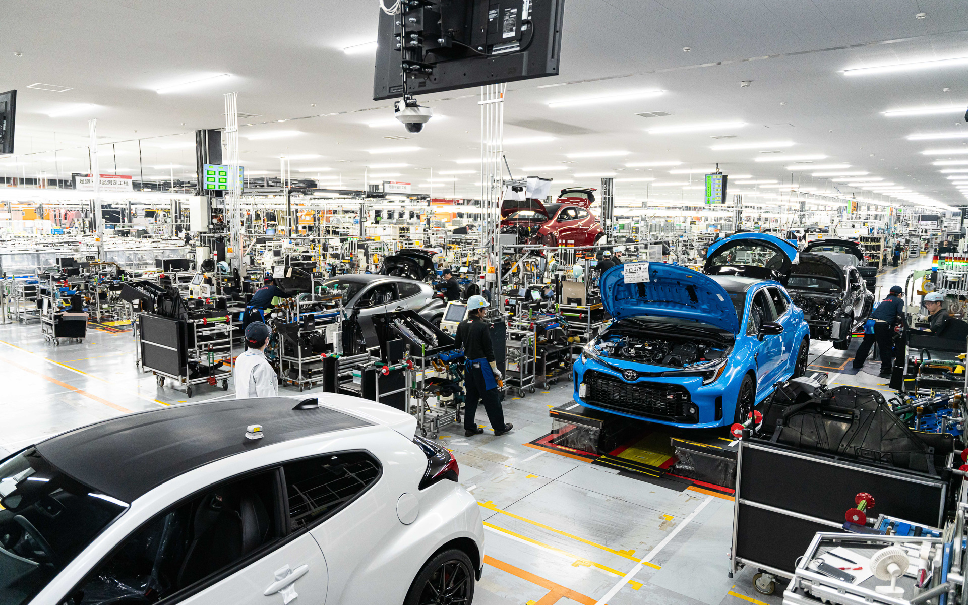 クルマの高さを変化させつつ各種部品を取り付け。右のラインと左のラインは同じ作業をしている。需要に応じてライン数を調整できる