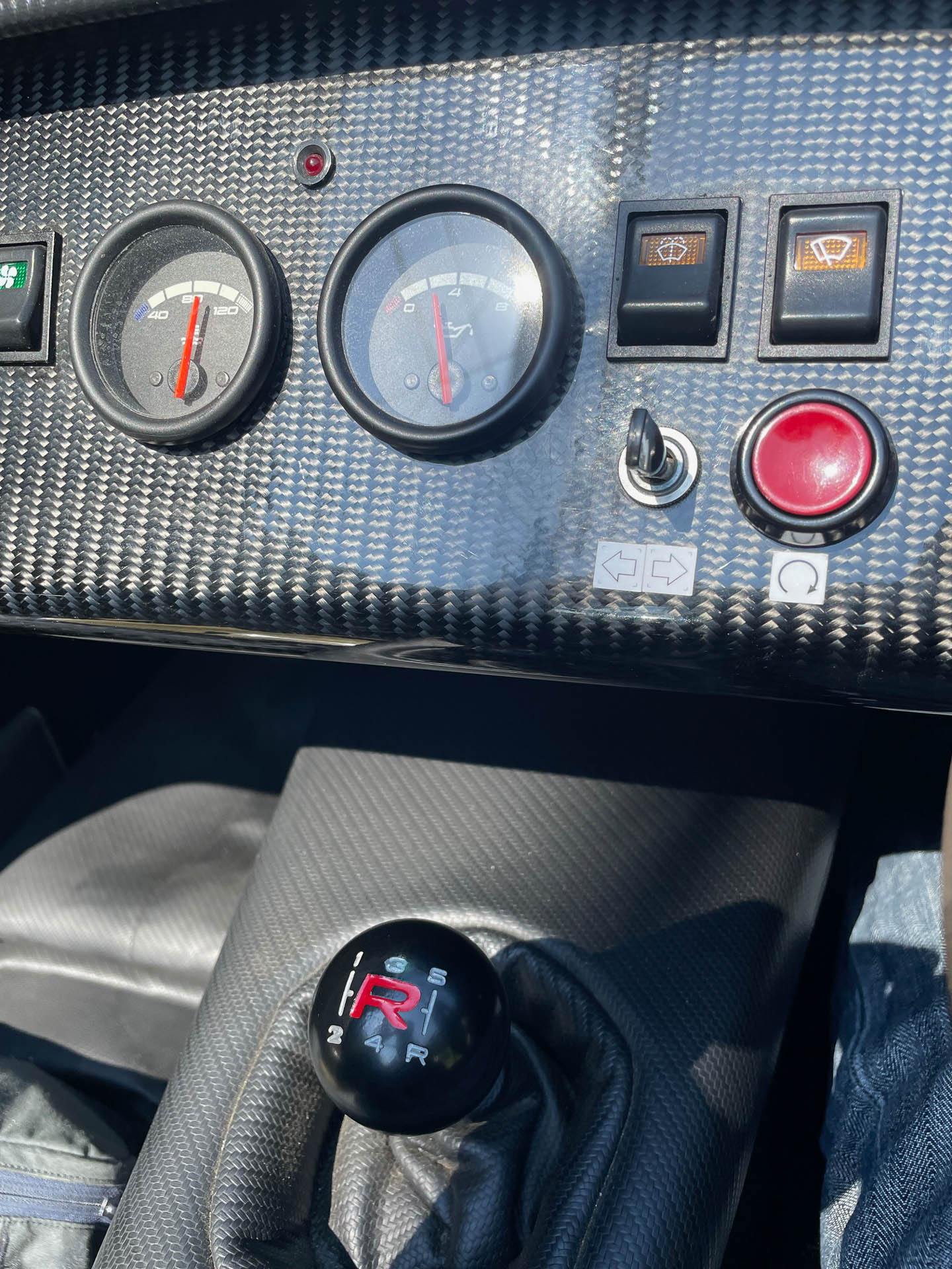 ダッシュボードのカーボンパネルに水温計と燃料計。ウインカーはタンブラスイッチなので自分で戻す。表示のテプラがケータハムらしい