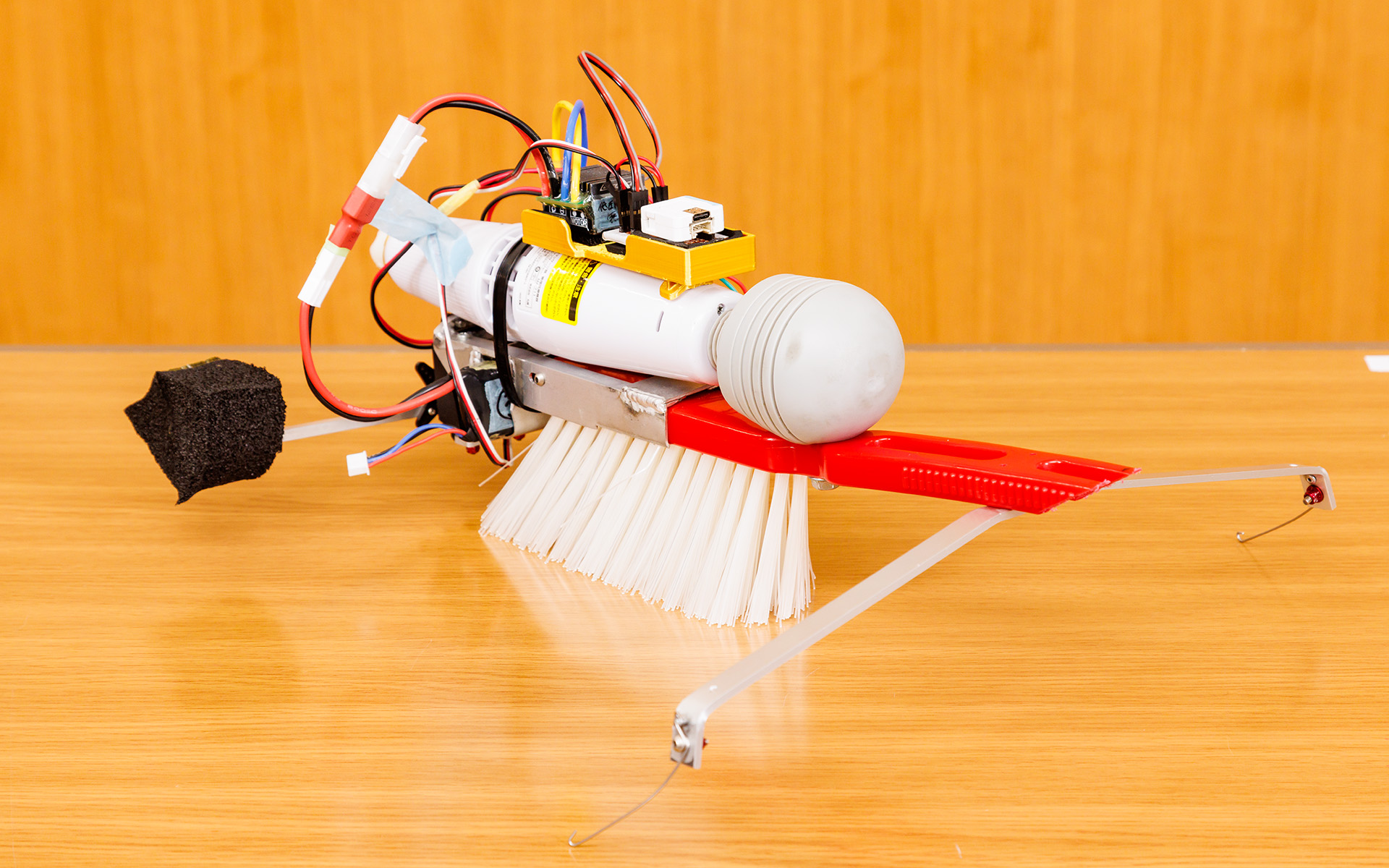 1.5号機をさまざまな角度から。電動マッサージ器の振動をブラシに伝え、ブラシのたわみを推進力にして前進。後方についているストックを動かして方向を変えるのだが、撮影時はストックが左にかたむいてしまっていた。制作費の総額は2万5532円