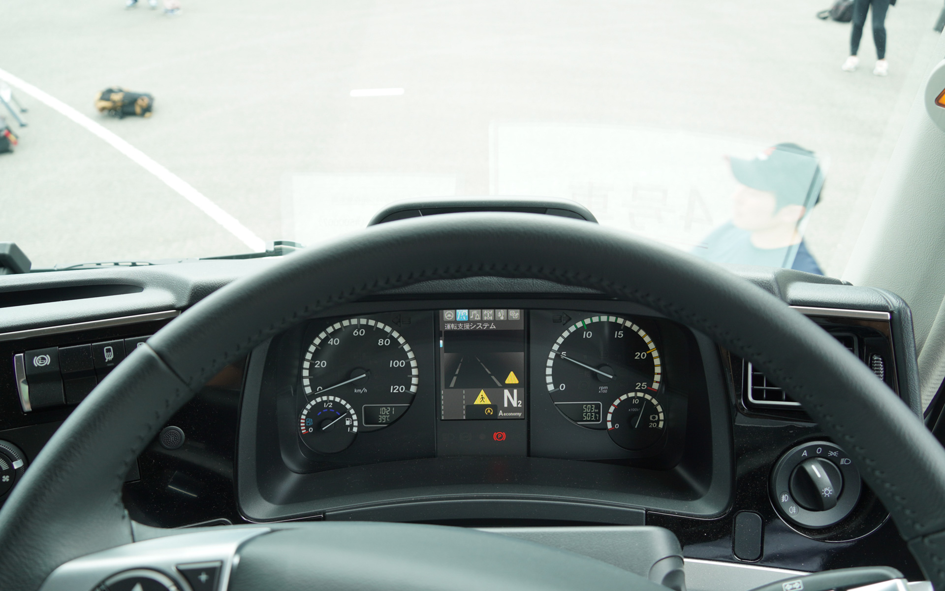 運転席から見て、すぐ前に人が横切っているところ。右側に注意マークが出ている。横断者の身長がもう少し低ければ、運転席から見えないこともありえるだろう