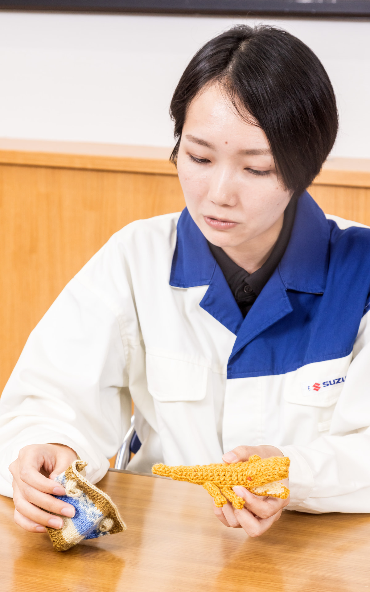 後方支援担当だったはずが、編み物でがっつり関わることになった徳弘千夏さん。見本として編んだというちびワニちゃんは、緑色の毛糸がなかったことから黄色い身体に赤い目のアルビノ種になったという。かわいいお洋服も着用可能