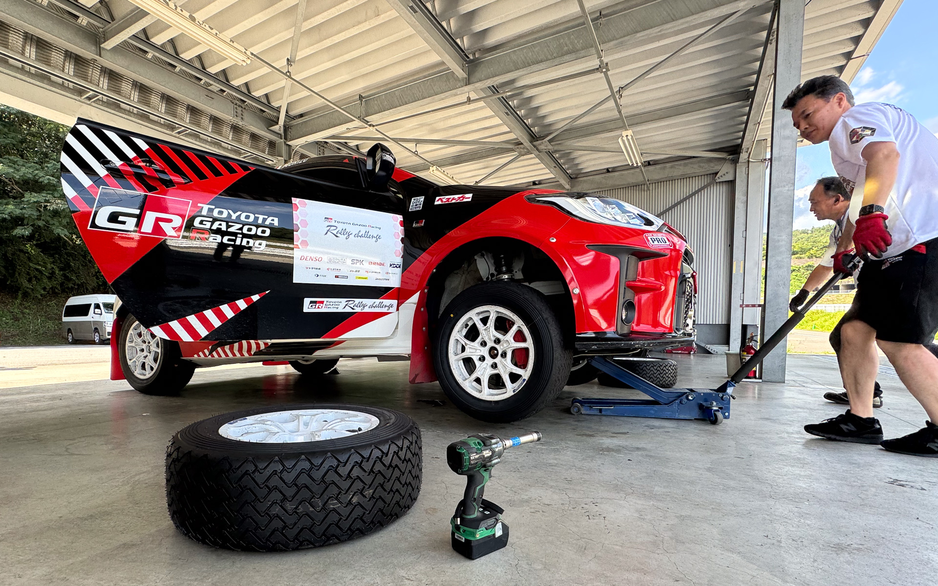 モリゾウ選手がドリフトしすぎるためにラリータイヤが減りまくる。で、タイヤ交換。タイヤ交換を行なうのはGR86の開発などで知られる凄腕技能養成部 GXの大阪晃弘氏。これも「かっこいい大人たちの姿」