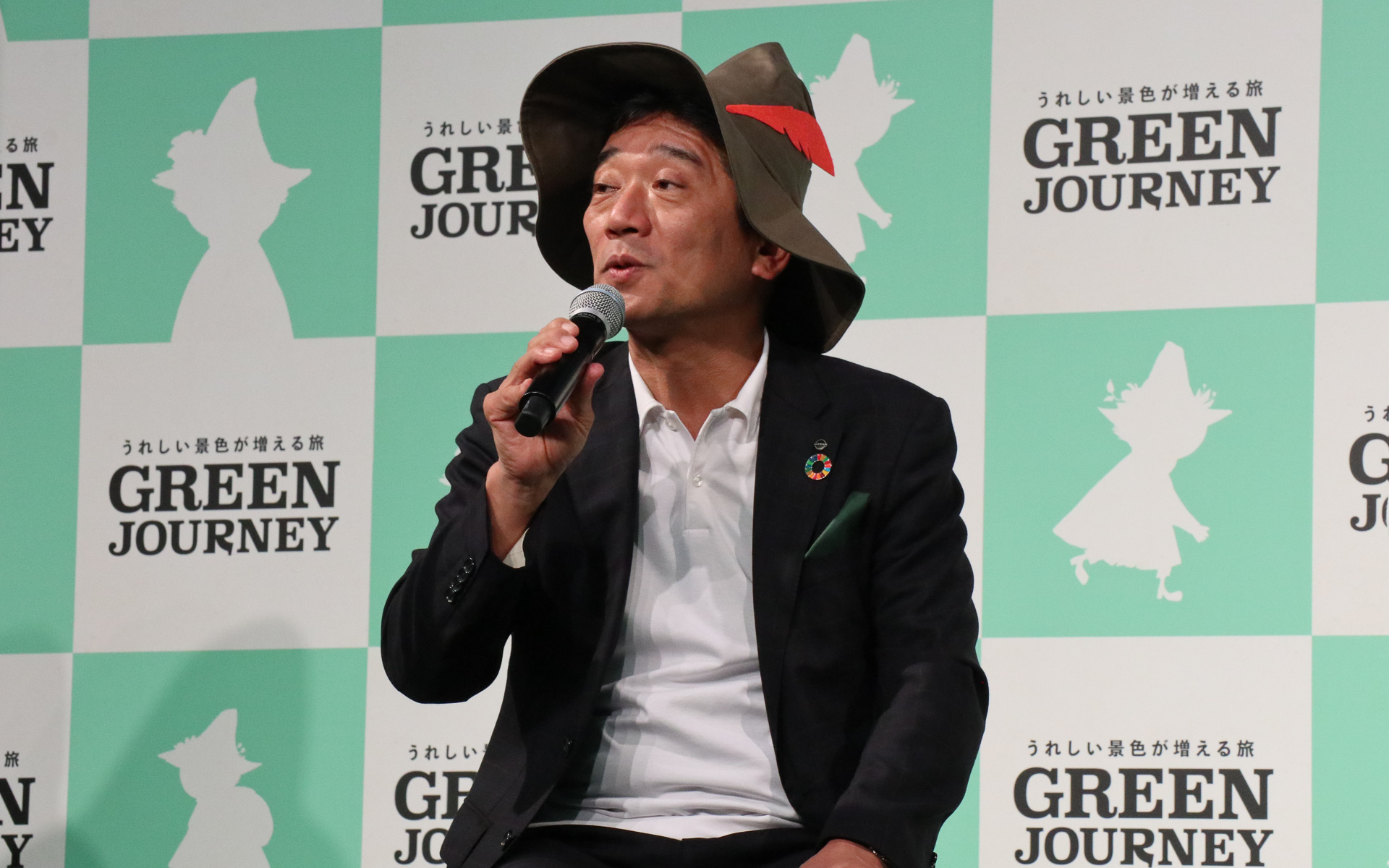 神田常務執行役員（左）と株式会社日本旅行 事業共創推進本部 チーフマネージャー 椎葉隆介氏（右）。GREEN JOURNEYのイメージキャラクターであるスナフキンを思わせる帽子を被って登場した