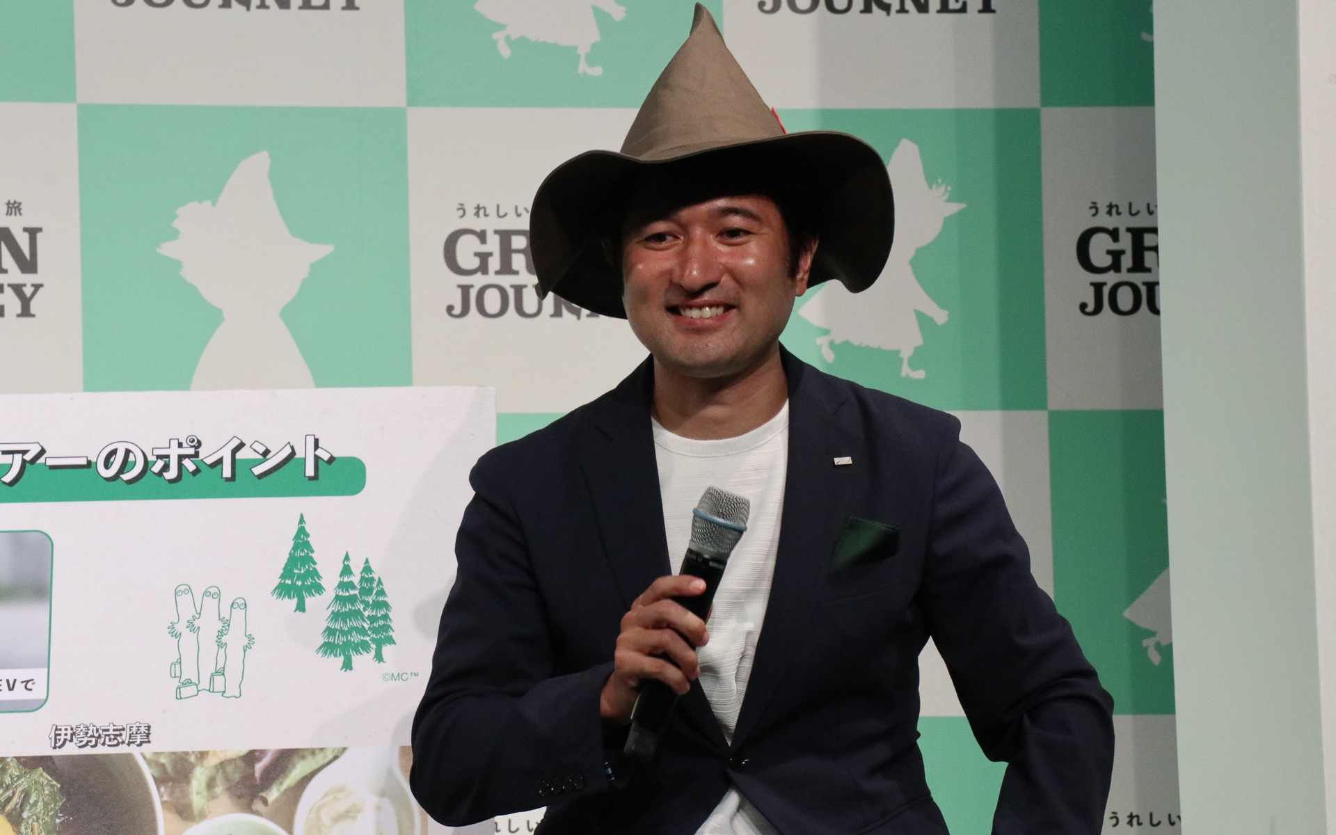 神田常務執行役員（左）と株式会社日本旅行 事業共創推進本部 チーフマネージャー 椎葉隆介氏（右）。GREEN JOURNEYのイメージキャラクターであるスナフキンを思わせる帽子を被って登場した