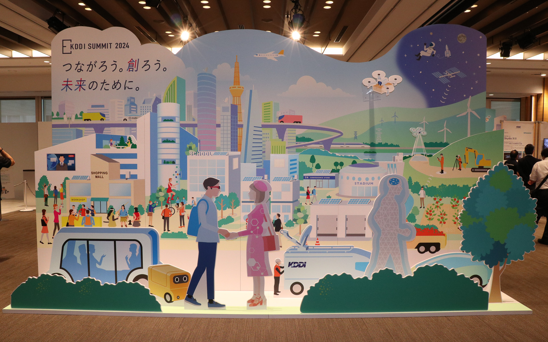 展示エリアの入口に設置されたKDDI SUMMIT 2024の展示コンセプト。左上に「つながろう。創ろう。未来のために。」という開催テーマが書かれている