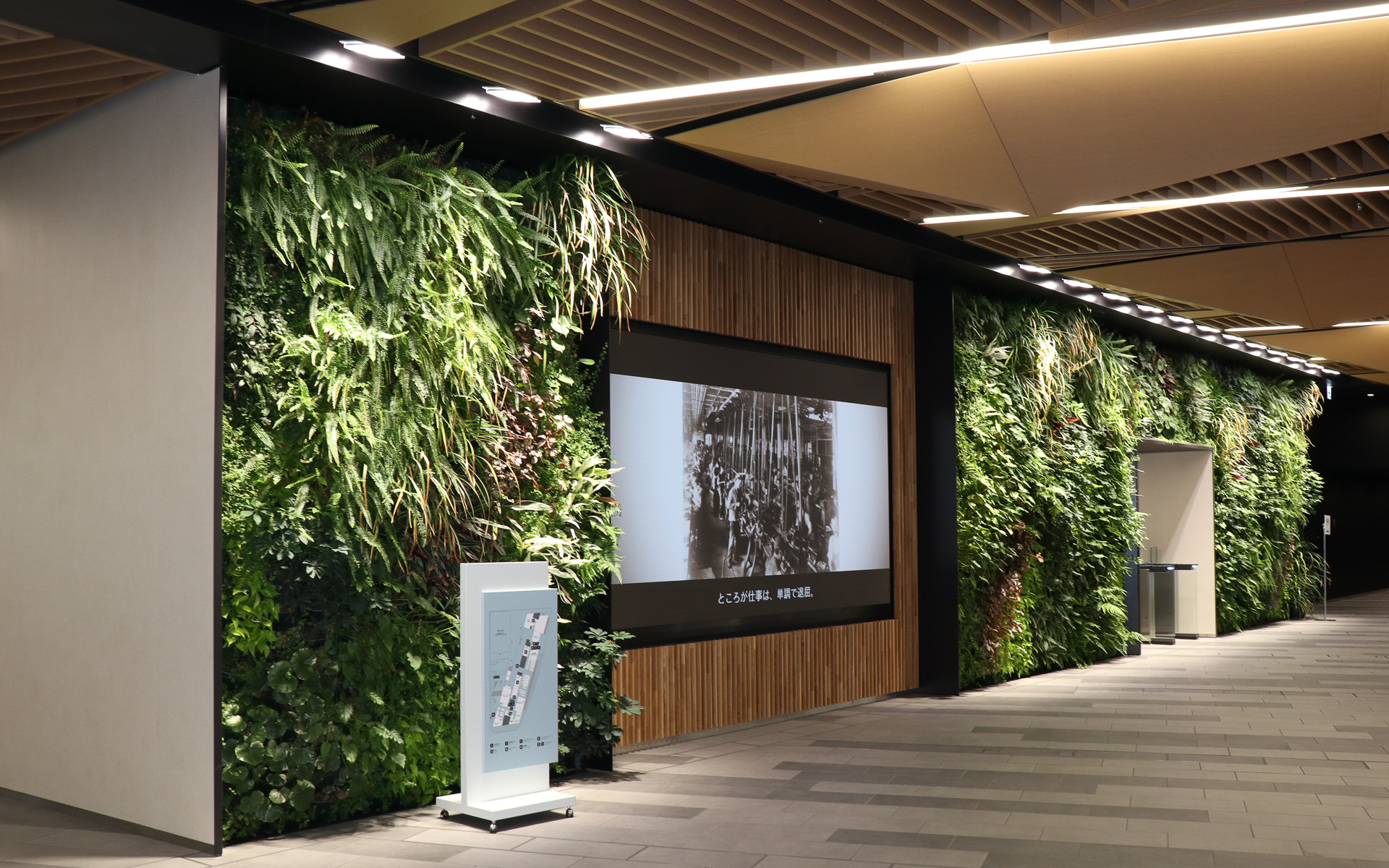 新本社は大地に立つ1本の樹と、その上に広がる空をコンセプトとしており、社屋内に木材を多用し、本物の植物を配したグリーンウォールも各所に設置。スパークプラグを手に持つレトロなデザインの人形も置かれていた