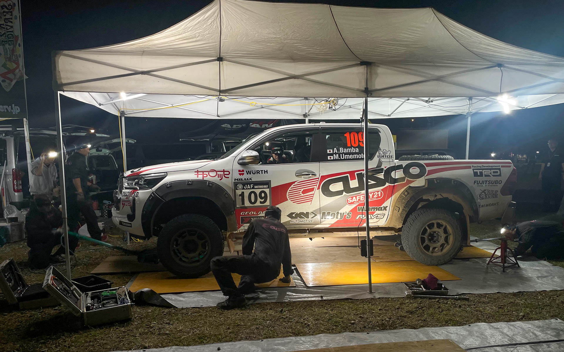 番場彬/梅本まどか組は大きなCUSCO YHジオランダー ハイラックスを豪快に走らせてXCRクラスで優勝。夜間のサービスではホイールが重そうだった