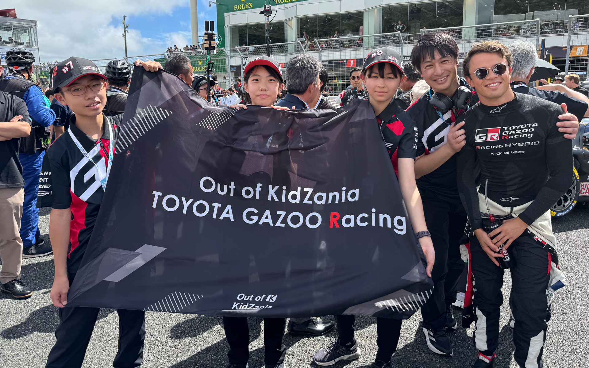 仲良く記念写真に応じるOut of KidZania TOYOTA GAZOO RacingのTGRキッズ広報3人と、TGR モータースポーツ技術室室長 加地雅也氏、ニック・デ・フリース選手