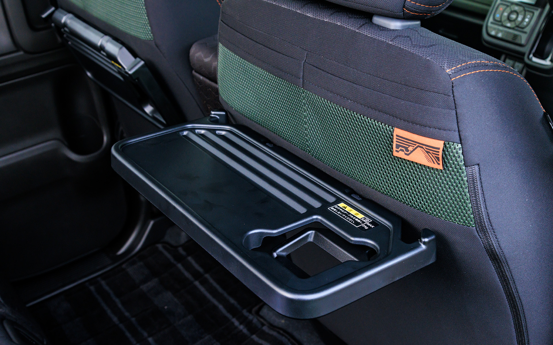 フロントシート背面に折り畳み式のテーブルを用意。上部にはメッシュタイプのポケットも。大型のタグには“トレイルランをしているスペーシア ギア”が描かれている