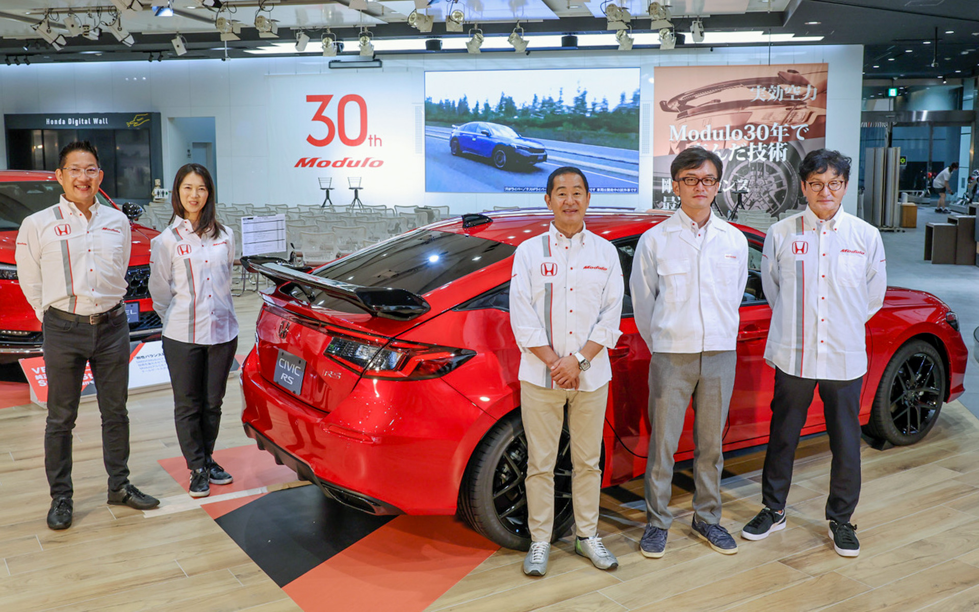 Moduloの30年の歩みが詰まった会場で、最新アイテムのシビック用テールゲートスポイラー（ウイングタイプ）を囲んでパチリ。いよいよ11月中旬に発売予定だそうですよ。既存のスポイラーを購入済みの方には、付け替えができる交換キットが「感謝価格」にて販売されるというから嬉しいですね