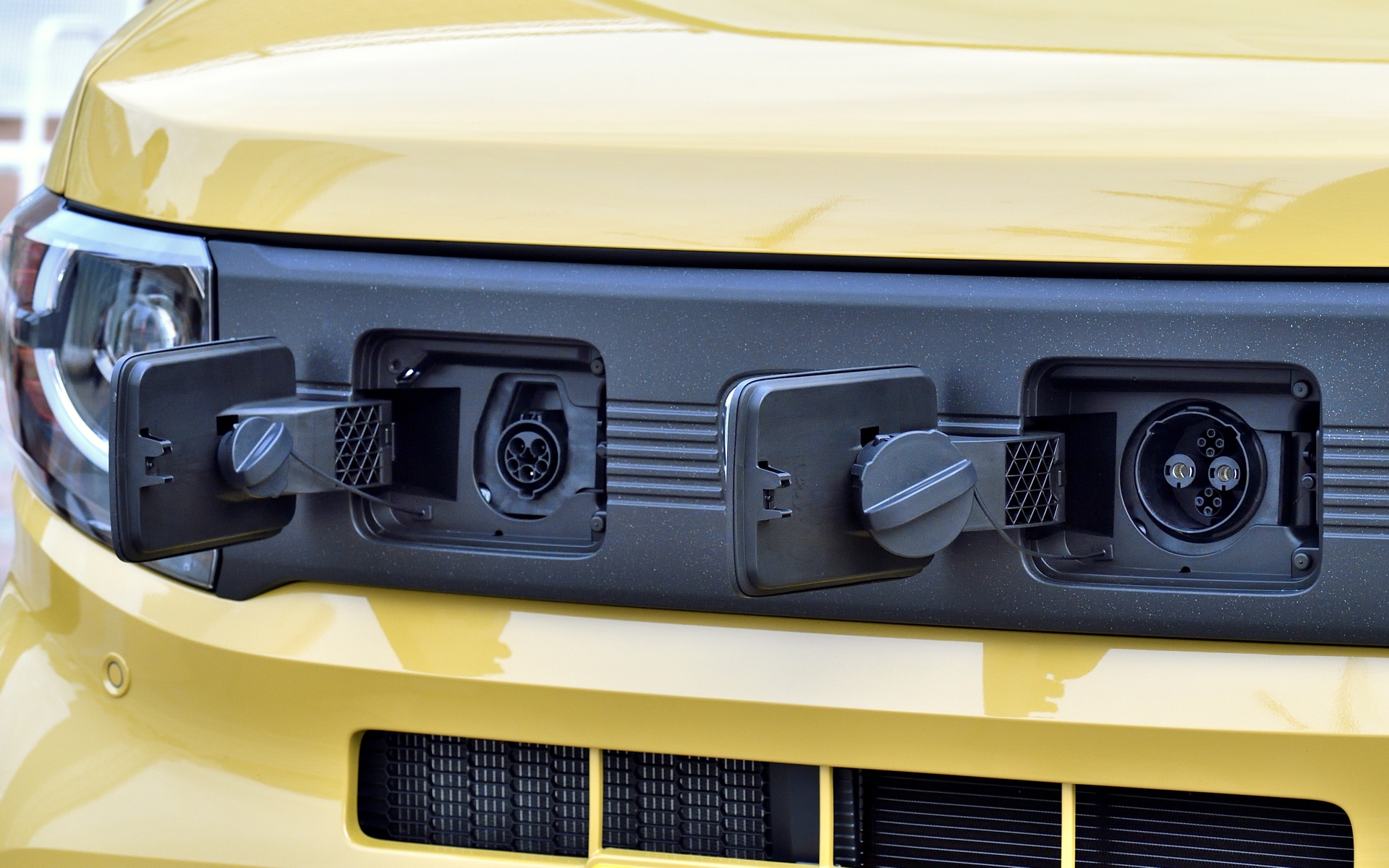 フロントグリルに給電ポートが付く。運転席側が普通充電用、助手席側が急速充電用。普通充電用リッドはドアロック連動式で、開けるときはドアロックが解除の状態であれば押すと開くもの。急速充電用リッドは室内のスイッチを押すと開くというように操作法が分けられている