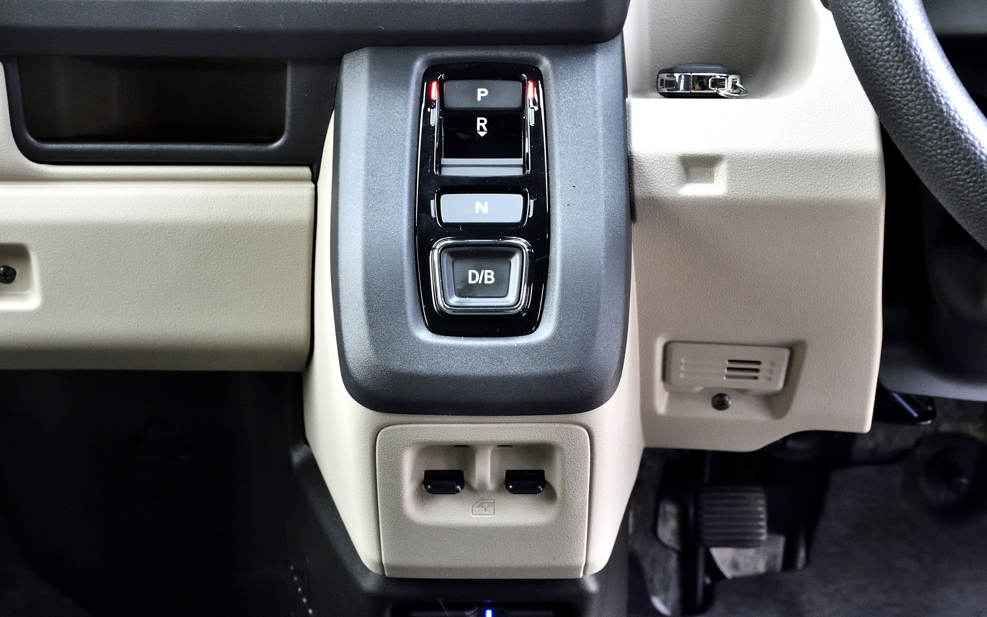 シフトはレバー式からボタン式に変更。上からP（パーキング）、R（リバース）、N（ニュートラル）で、いちばん下がD（ドライブ）とアクセルオフ時に回生ブレーキが強めに掛かる「Bレンジ」の切り替えボタン。手前の面にあるのがパワーウィンドウのスイッチだが、運転席側からワンタッチで全開、全閉できる機能がなくなった。サイドブレーキは足踏みの機械式のまま